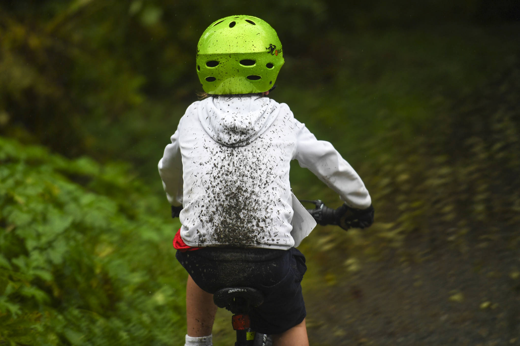 Mud splatters a rider during the Douglas Dirt Derby Youth Bike Race at Savikko Park and the Treadwell Historic Trail on Saturday, Oct. 5, 2019. The event was organized by the Juneau Freewheelers Bicycle Club. (Michael Penn | Juneau Empire)