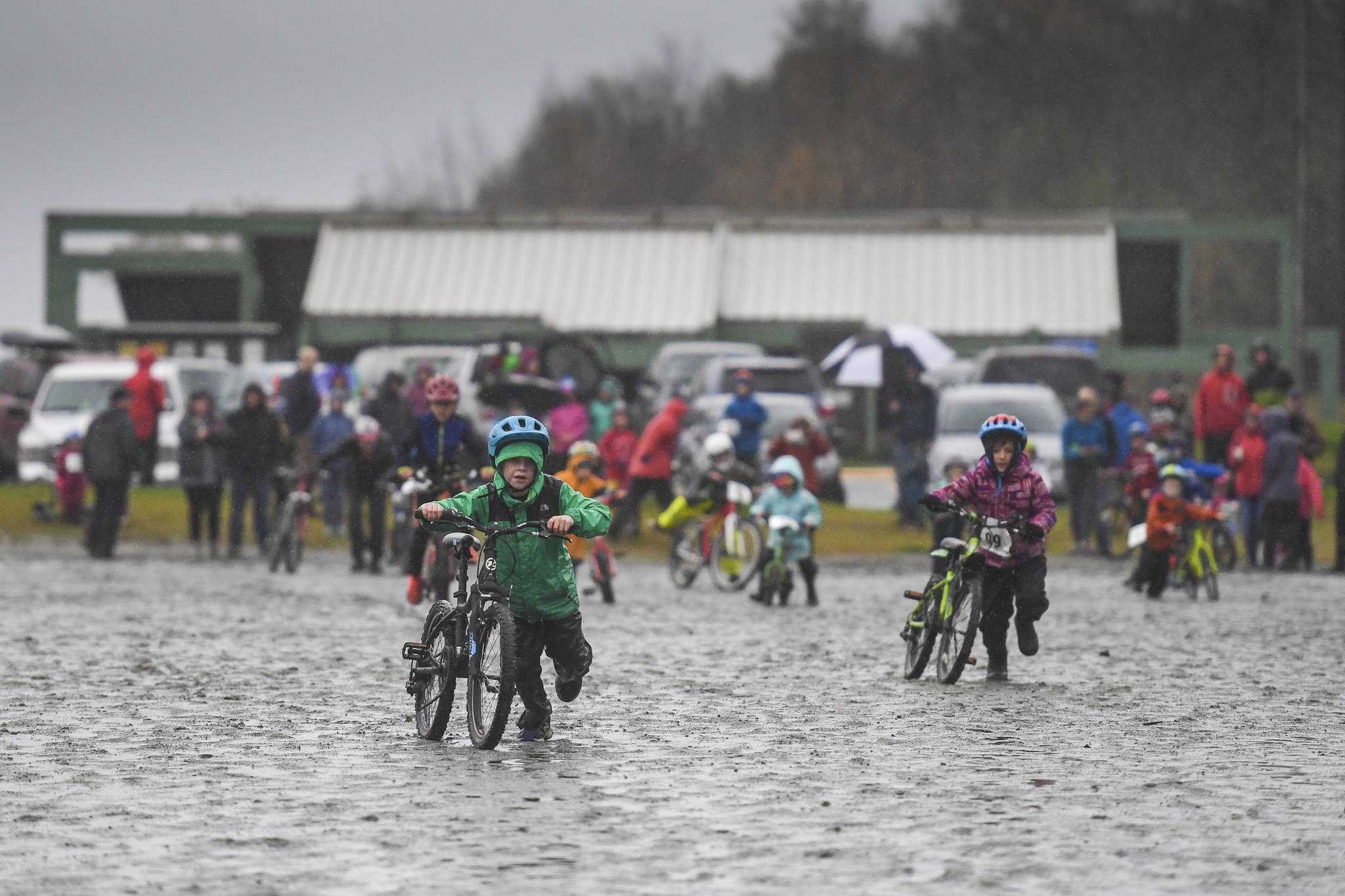 Riders run their bikes across a muddy ball field as the start of the Douglas Dirt Derby Youth Bike Race for 5 to 7-year-olds at Savikko Park and the Treadwell Historic Trail on Saturday, Oct. 5, 2019. The event was organized by the Juneau Freewheelers Bicycle Club. (Michael Penn | Juneau Empire)
