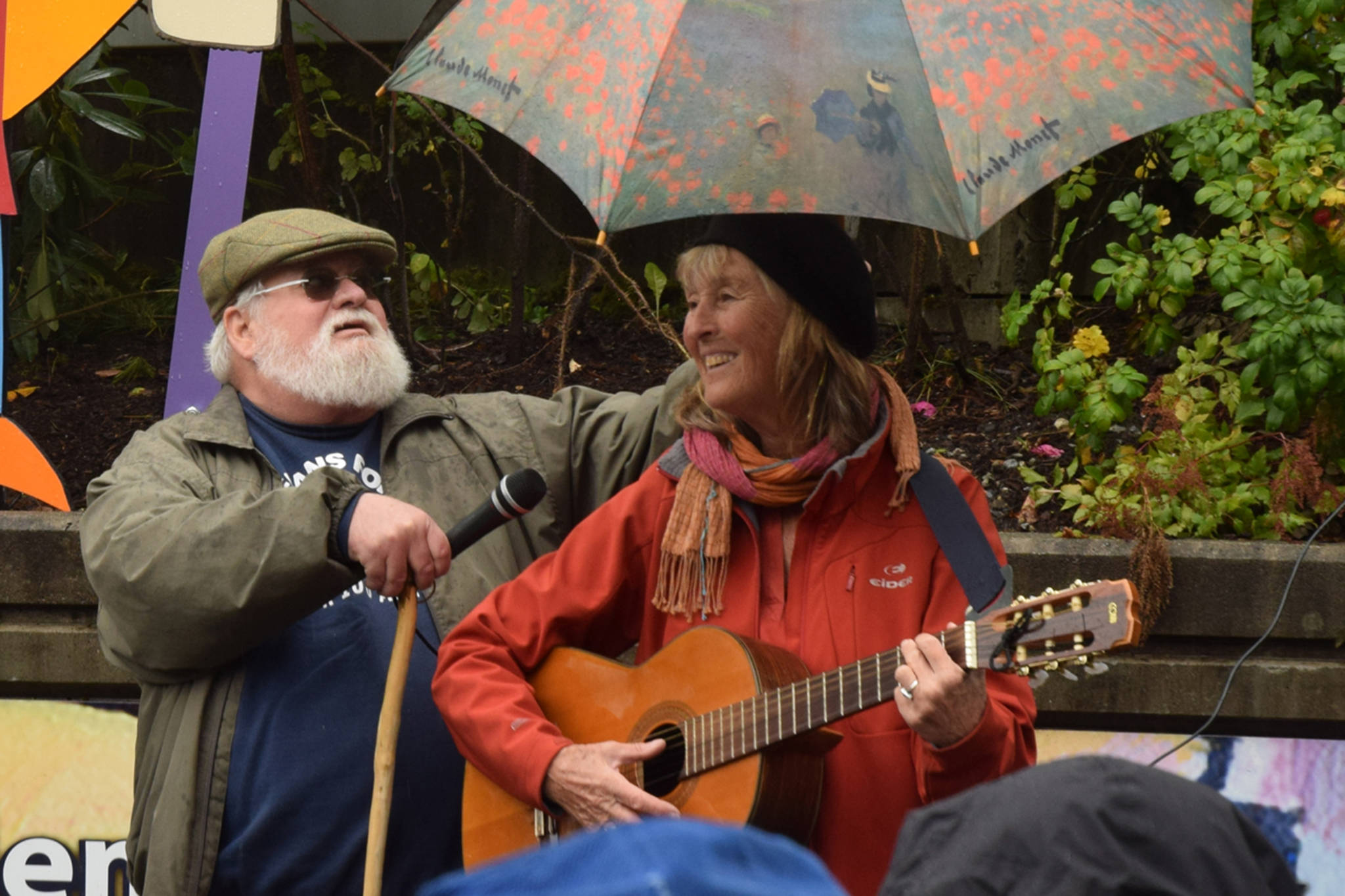 Phil Smith holds a microphone for Linda Buckley as she sings in August 2015. The songwriter, poet and retired teacher is publishing her first children’s book soon. It will have a November launch party in Juneau. (Michael Penn | Juneau Empire File)