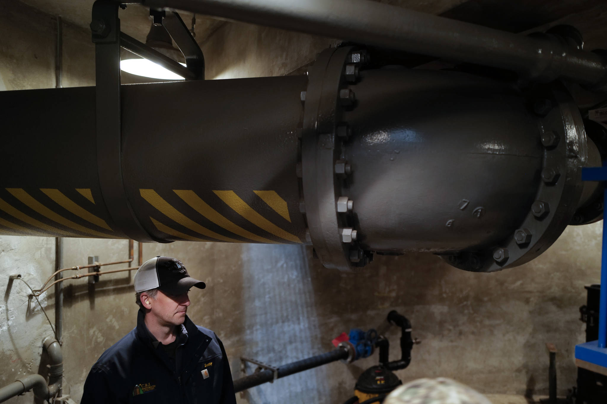Scott Simonson, a senior wastewater collection officers for the city, stands underneath an outgoing wastewater pipe at theOuter Drive Pumping Station downtown on Friday, Oct. 11, 2019. The three pumps were overwhelmed during last weekend’s storm and caused a backup of sewage into the Mayor Bill Overstreet Park utilities building. (Michael Penn | Juneau Empire)