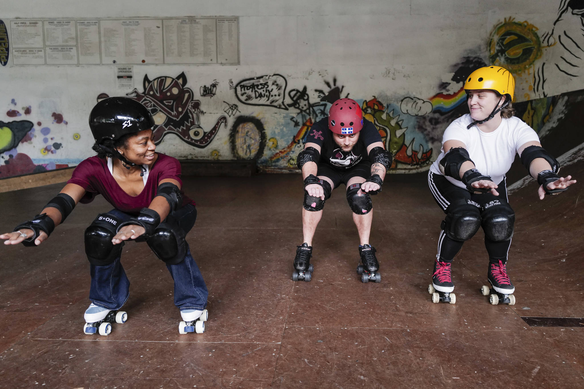 Jennifer Gross, right, and Shabadrang Khalsa, who skate with the Juneau Rollergirls, teach Empire reporter Michael S. Lockett how to rollerskate at the Pipeline Skate Park on Friday, Oct. 11, 2019. (Michael Penn | Juneau Empire)