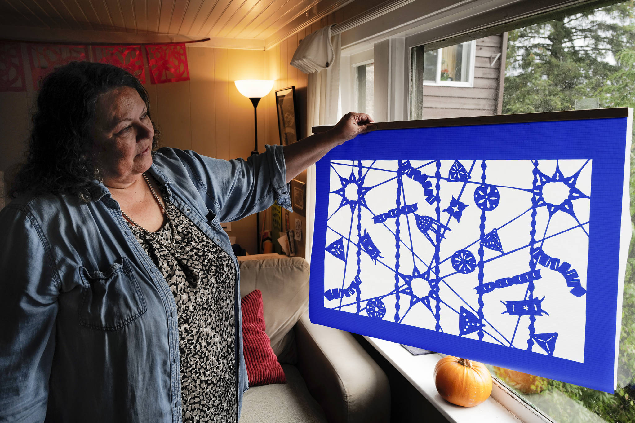 Artist Merridy L. Davis holds one of her new nylon cutouts against a window at her downtown home on Friday. Learn more about her upcoming show in the video below. (Michael Penn | Juneau Empire)