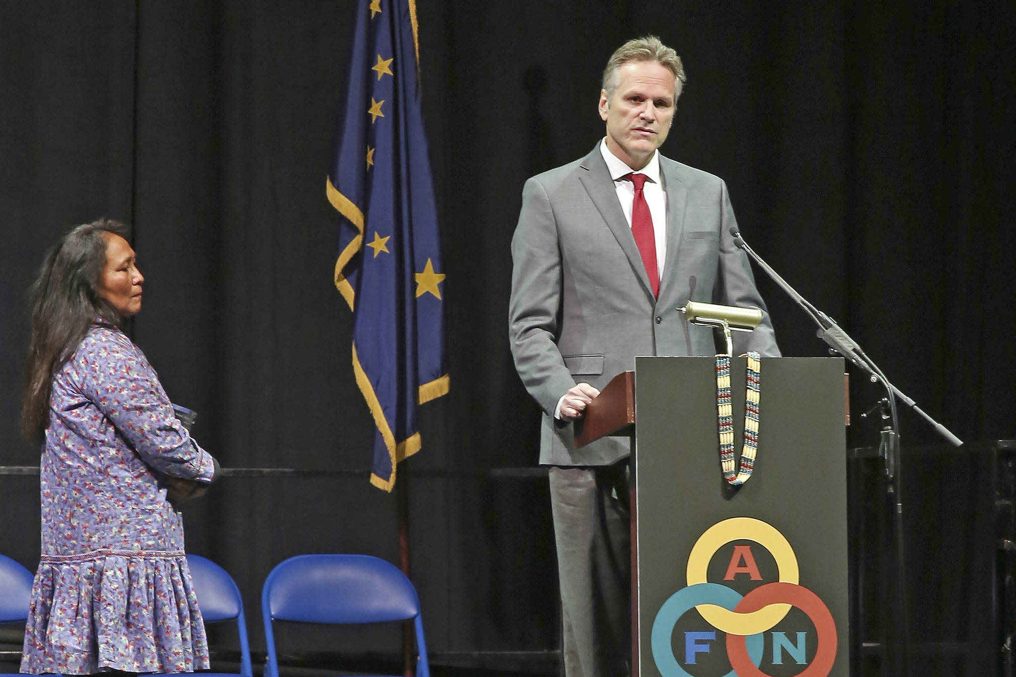 Gov. Mike Dunleavy gives his State of Alaska Address with his wife Rose Dunleavy at his side during the 2019 Alaska Federation of Natives Convention Thursday, Oct. 17, 2019, in Fairbanks, Alaska. Republican Alaska Gov. Mike Dunleavy outlined plans aimed at improving public safety in rural Alaska during a speech Thursday to a major gathering of Alaska Natives that was interrupted by protests. (Eric Engman/Fairbanks Daily News-Miner via AP)