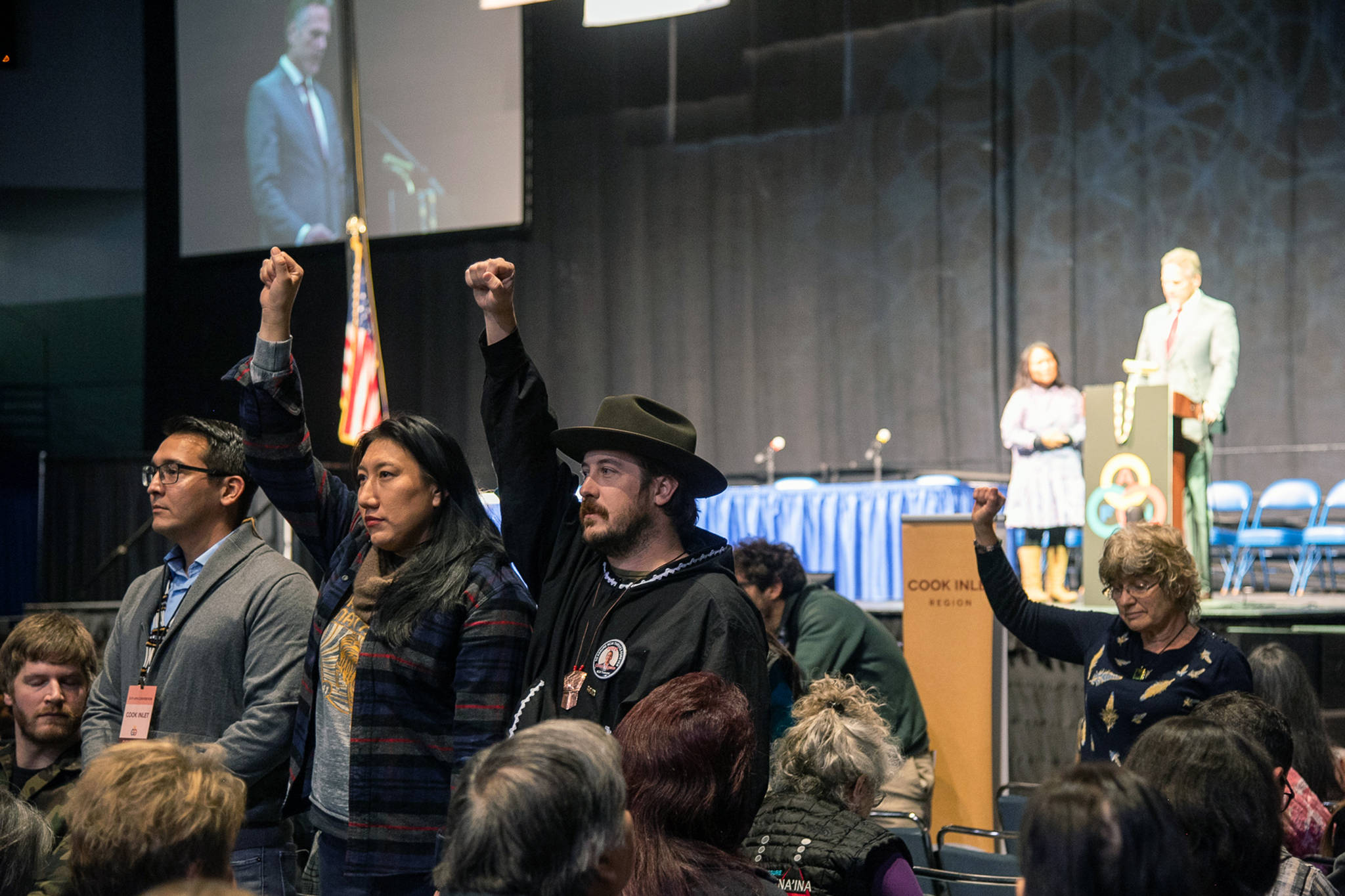 Protesters raise their fists during Gov. Mike Dunleavy’s speech at the Alaska Federation of Natives Contention, Thursday, Oct. 18,2019. (Courtesy Photo | Defend the Sacred Alaska)