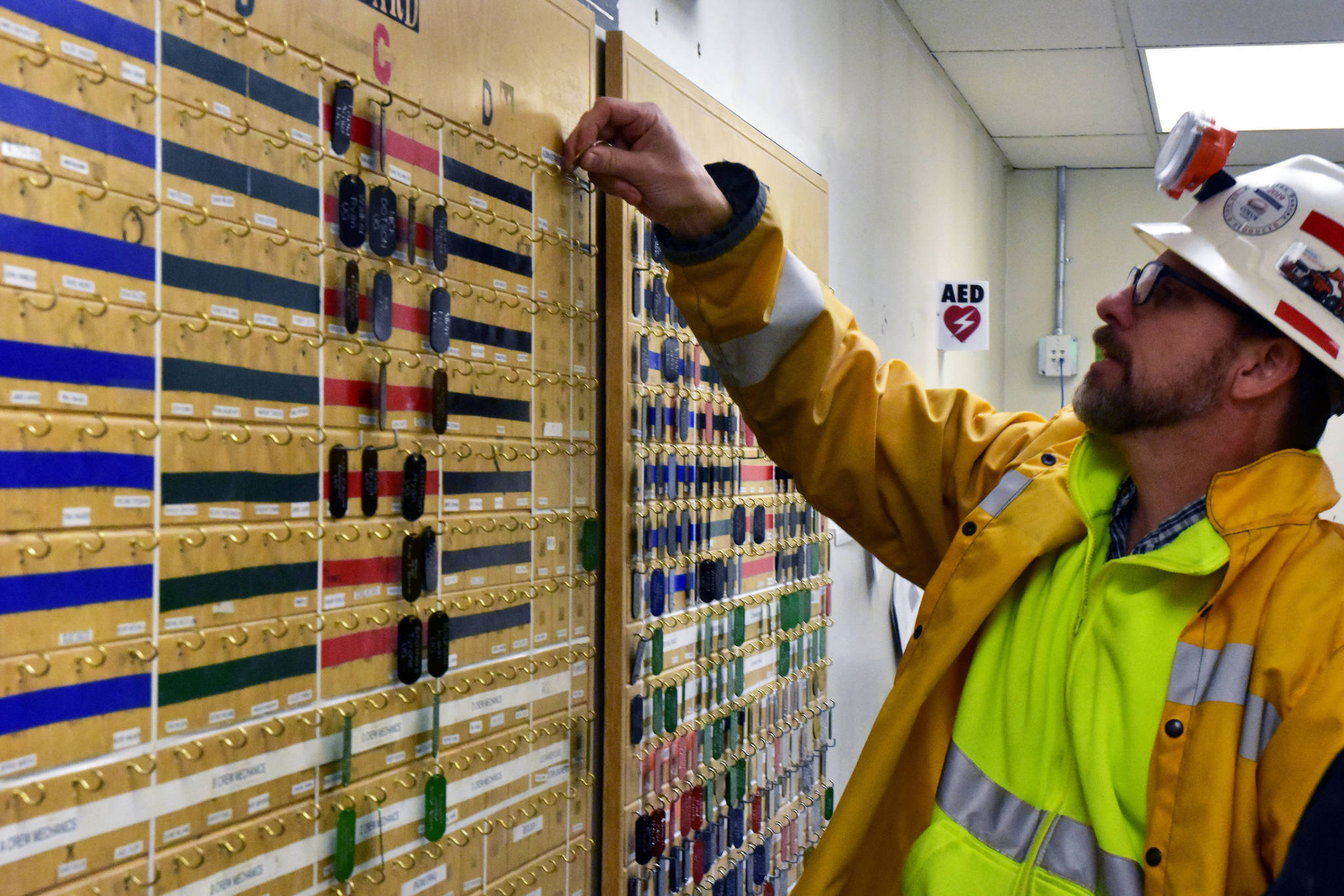 Mark Kiessling, general manger at the Kensington Mine moves a brass tag used to track how many people are currently in the mine on Monday, Oct. 14, 2019. (Peter Segall | Juneau Empire)
