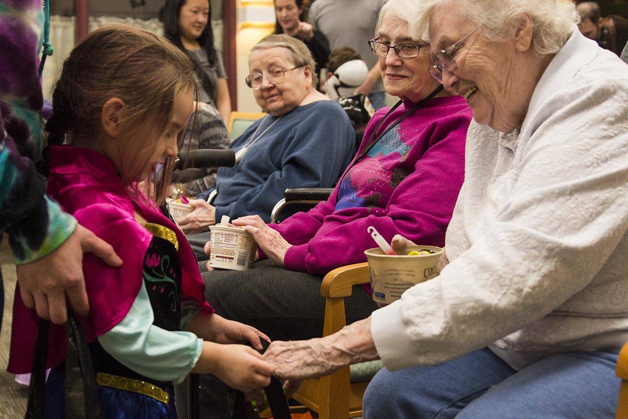 Lilly, 3, receives some candy from Betty Hunt as members of the Parents as Teachers program and a number of children visited the Juneau Pioneer Home to have an early Halloween with the residents on Tuesday, Oct. 22, 2019. (Michael S. Lockett | Juneau Empire)
