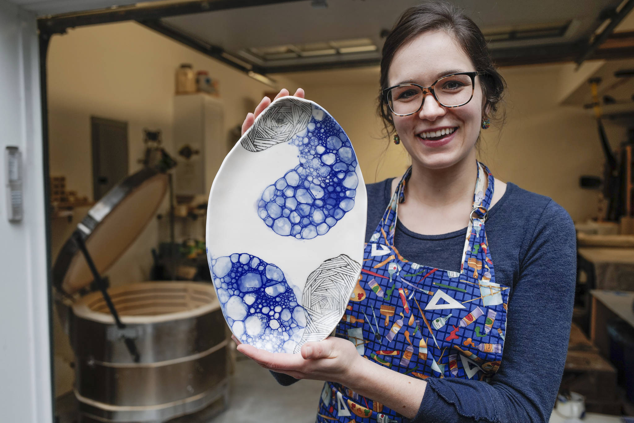 Mercedes Muñoz holds a ceramic plate at her home studio on Monday, Oct. 28, 2019. Muñoz is showing her work at Coppa for First Friday. (Michael Penn | Juneau Empire)