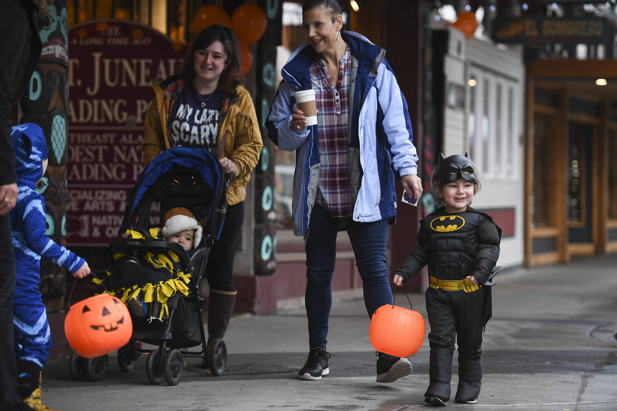 Chloe Caordova, left, makes her way down Franklin Street with her children, Ashton, 1, and Leonardo, 3, and Rochelle Sabadin during the Trick or Treat Downtown event on Thursday, Oct. 31, 2019. More than 70 business put out orange balloons to participate in the event aimed at young children. (Michael Penn | Juneau Empire)