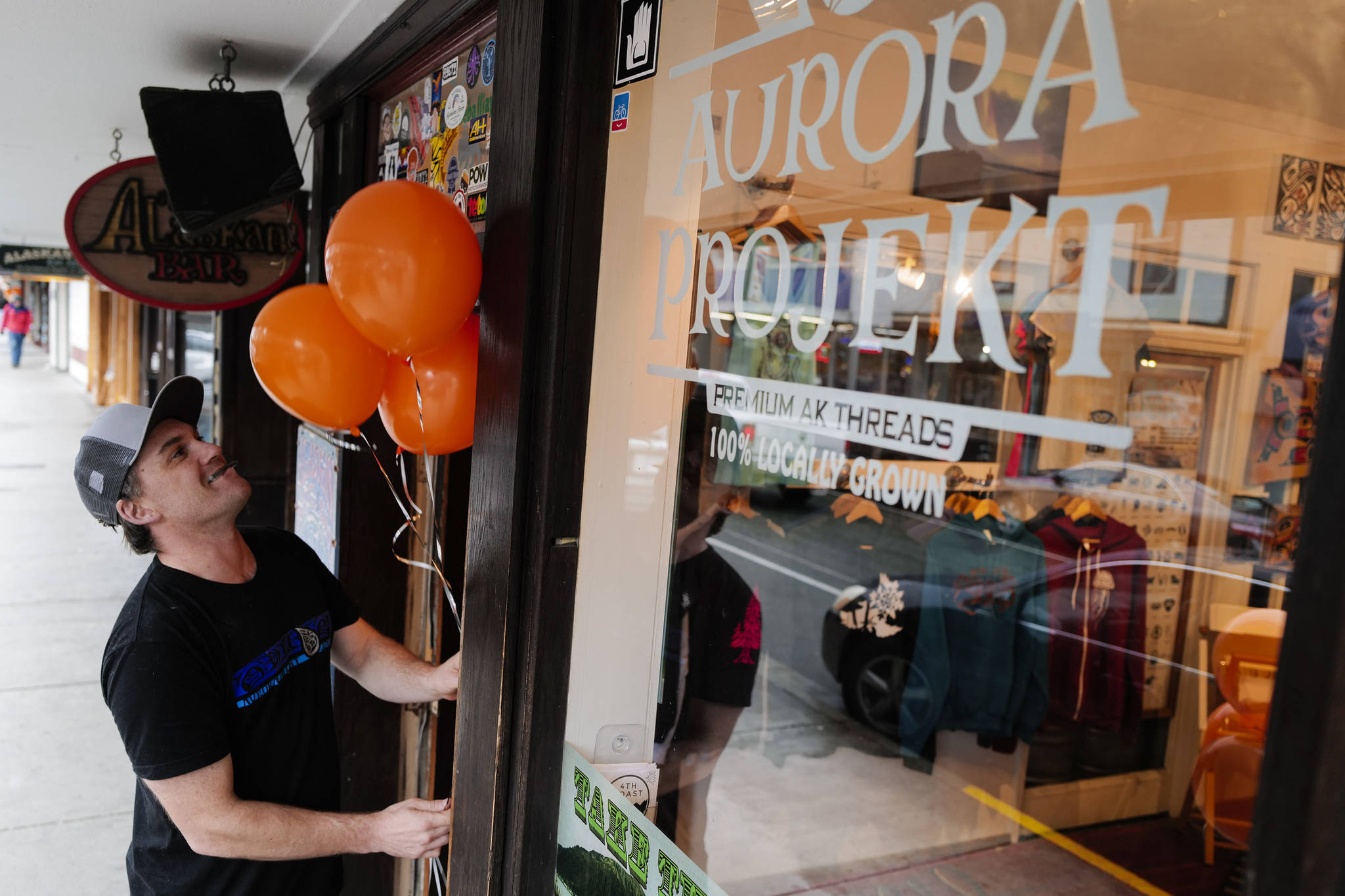Scott Baxter, owner of Aurora Projekt, puts out balloon for the Trick or Treat Downtown event on Thursday, Oct. 31, 2019. More than 70 business put out orange balloons to participate in the event aimed at young children. (Michael Penn | Juneau Empire)