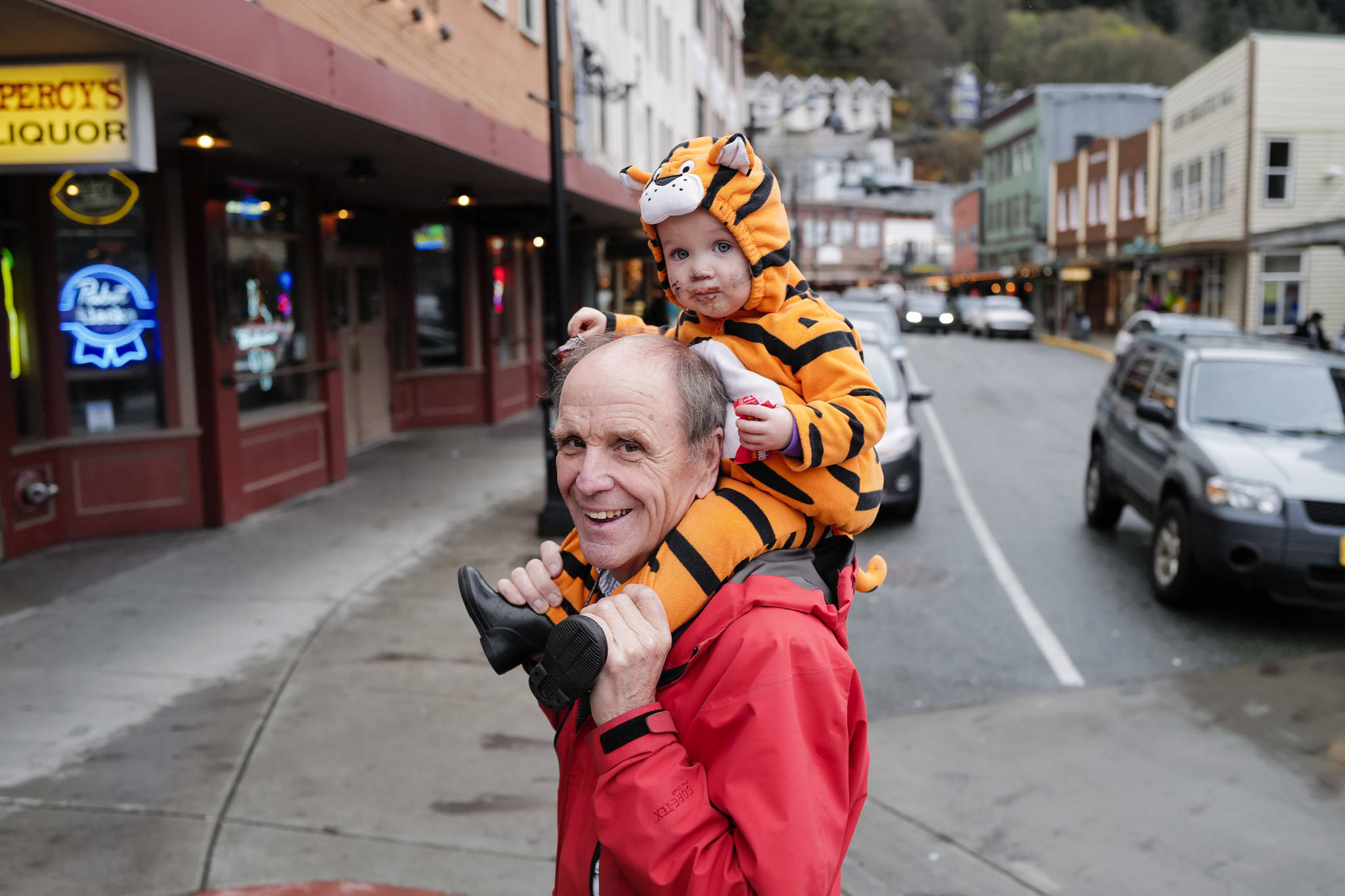 Bruce Denton carries his granddaughter, Hali Hall, 1, during the Trick or Treat Downtown event on Thursday, Oct. 31, 2019. More than 70 business put out orange balloons to participate in the event aimed at young children. (Michael Penn | Juneau Empire)