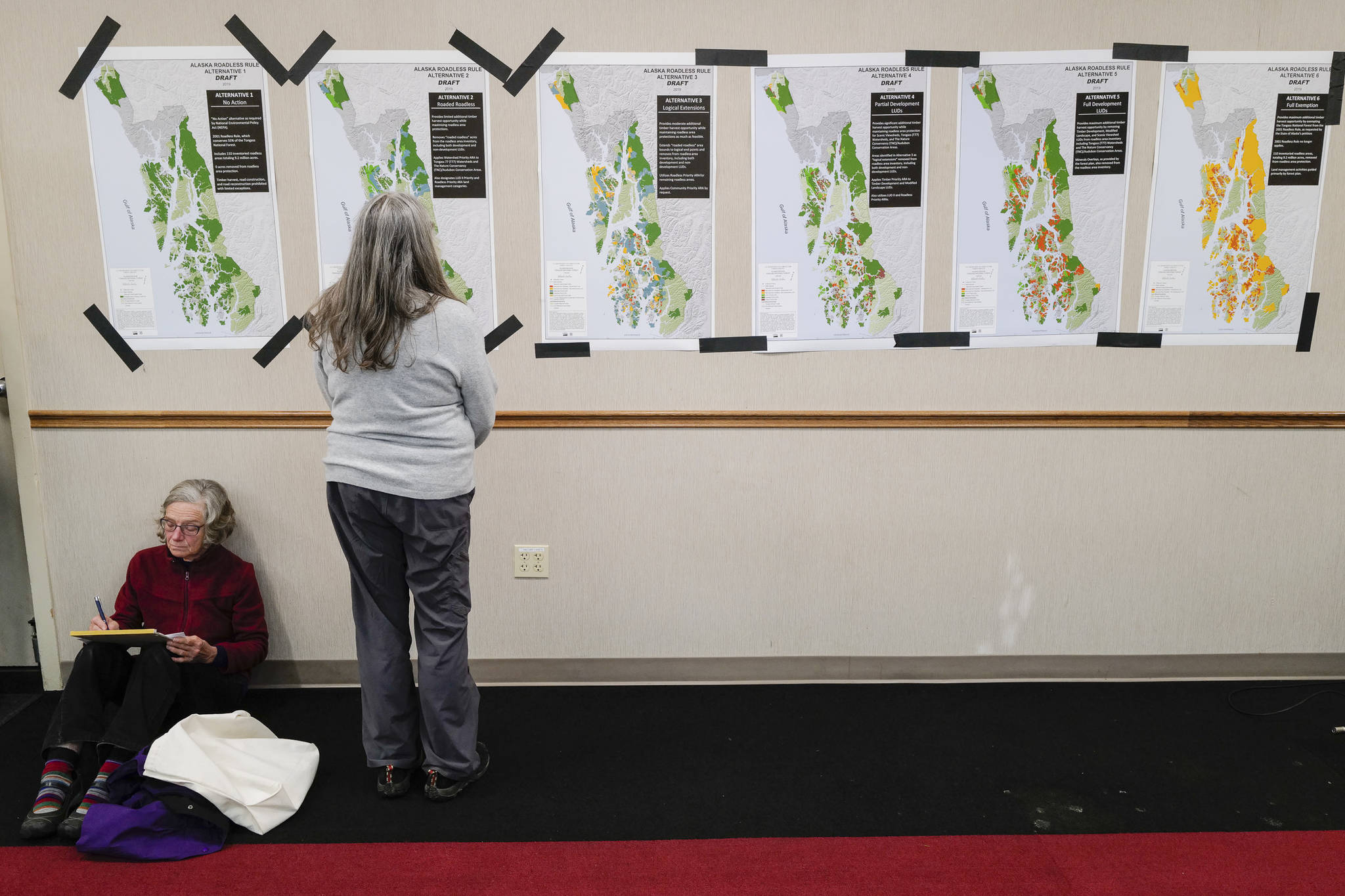 A Juneau resident studies maps for the six Alaska Roadless Areas Draft Environmental Impact Statement drafts during an informational meeting by U.S. Department of Agriculture Forest Service at Elizabeth Peratrovich Hall on Monday, Nov. 4, 2019. (Michael Penn | Juneau Empire)