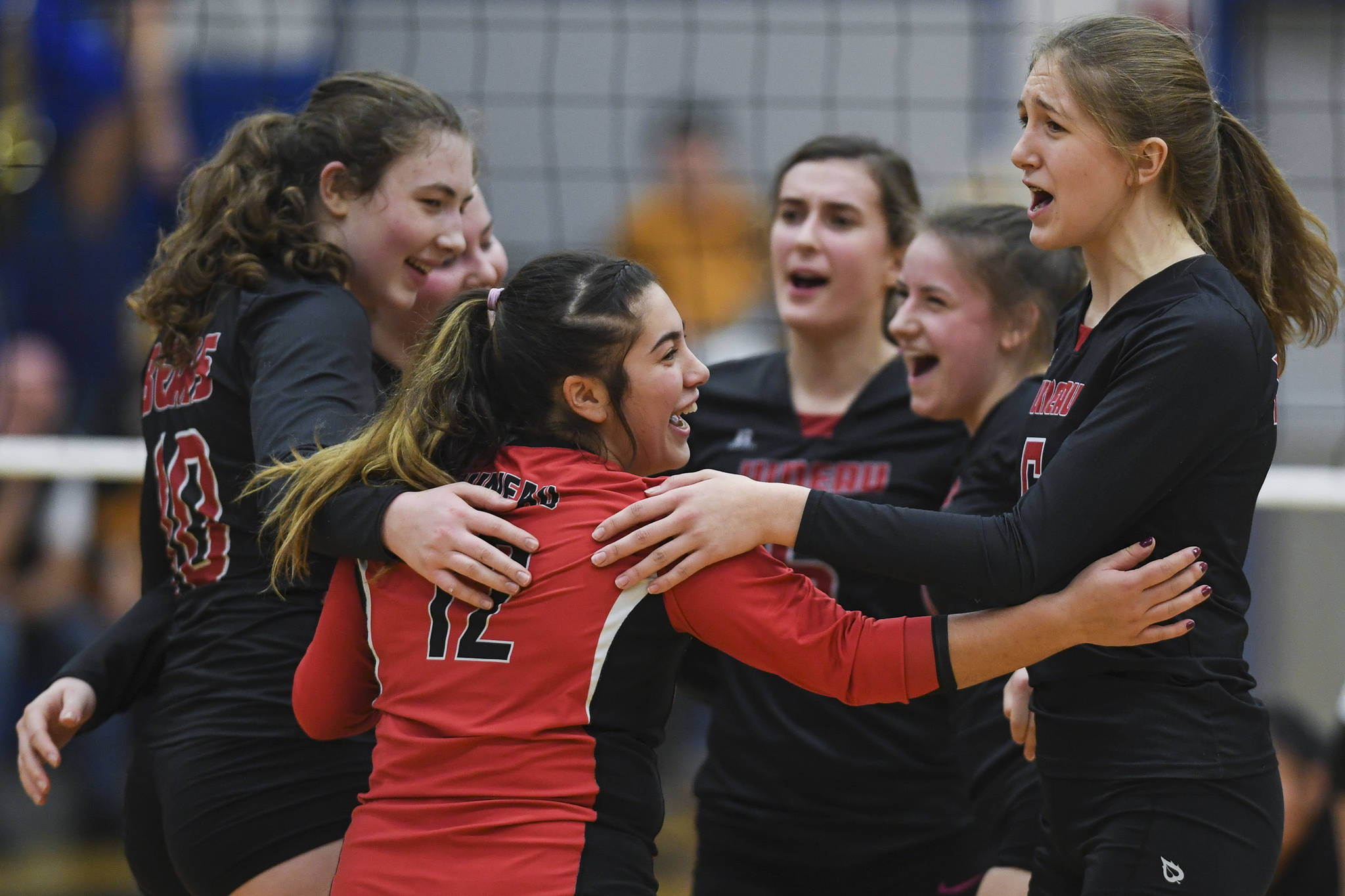 Juneau-Douglas’ Paige Adams, center, celebrates a point with her teammates against Thunder Mountain during the Region V Volleyball Tournament at Thunder Mountain High School on Friday, Nov. 8, 2019. JDHS won 25-22, 26-24, 25-20. (Michael Penn | Juneau Empire)