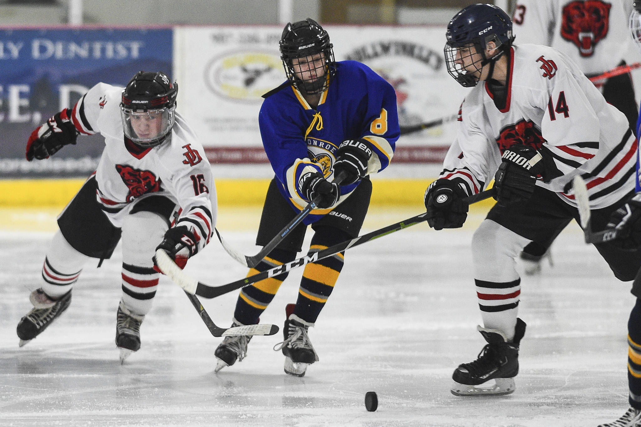 Juneau-Douglas’ Zac Stagg, left, and Max McHenry, right, take the puck away from Monroe Catholic’s Bella Knavel at the Treadwell Arena on Friday, Nov. 15, 2019. JDHS won 10-0. (Michael Penn | Juneau Empire)