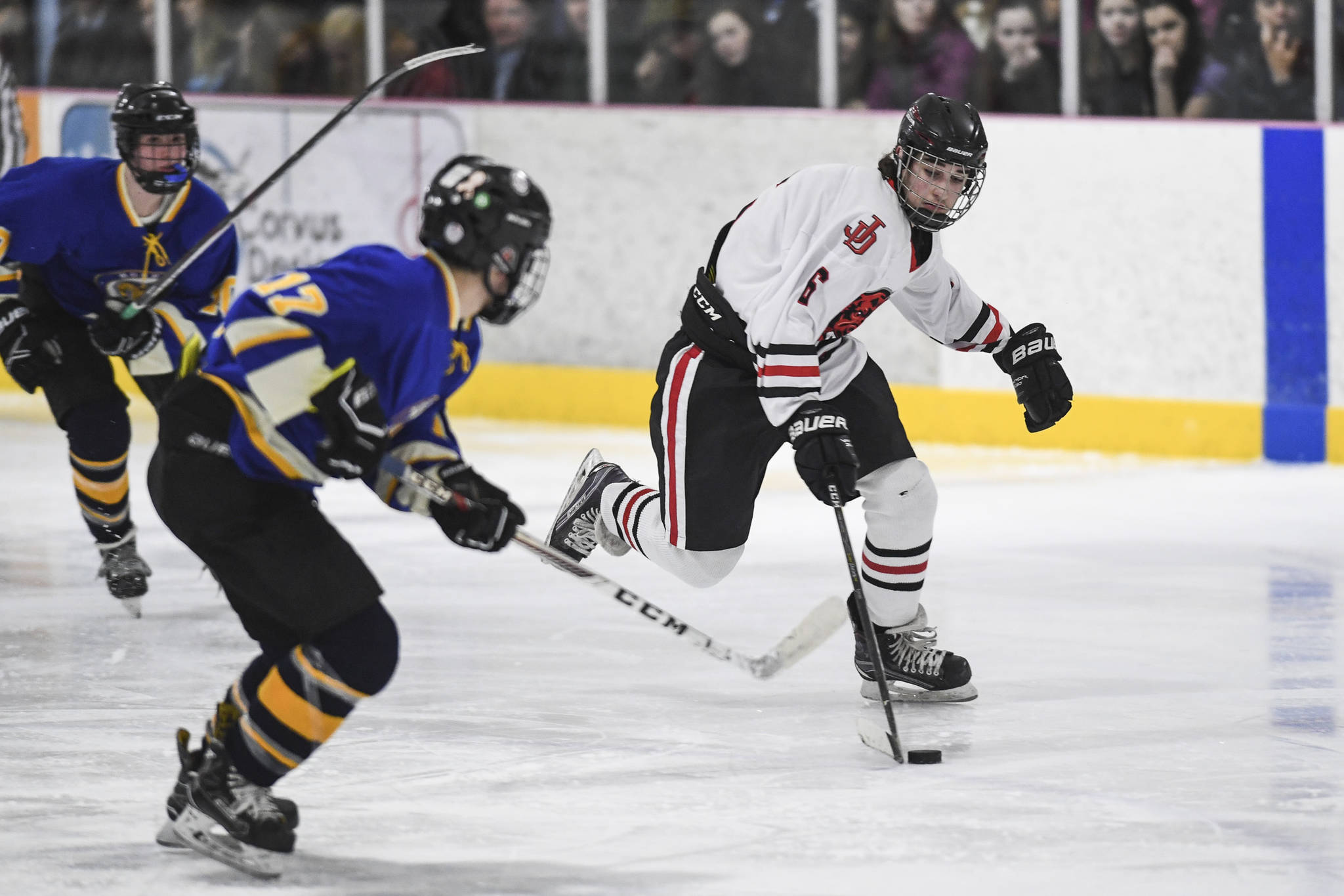 Juneau-Douglas’ Colter Polley moves the puck against Monroe Catholic’s Miles Fowler at the Treadwell Arena on Friday, Nov. 15, 2019. JDHS won 10-0. (Michael Penn | Juneau Empire)