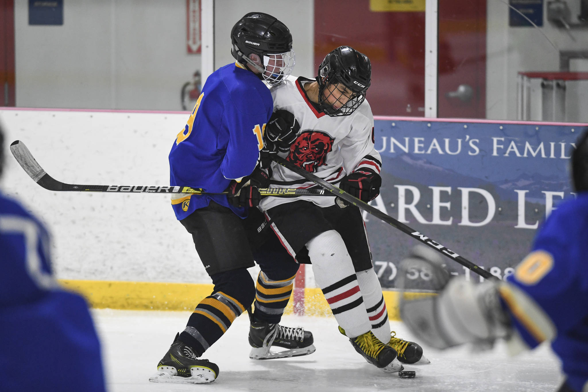 Juneau-Douglas’ Andre Peirovi, right, gets tied up against Monroe’s Dom Coiley in the second period at the Treadwell Arena on Friday, Nov. 15, 2019. JDHS won 13-0. (Michael Penn | Juneau Empire)