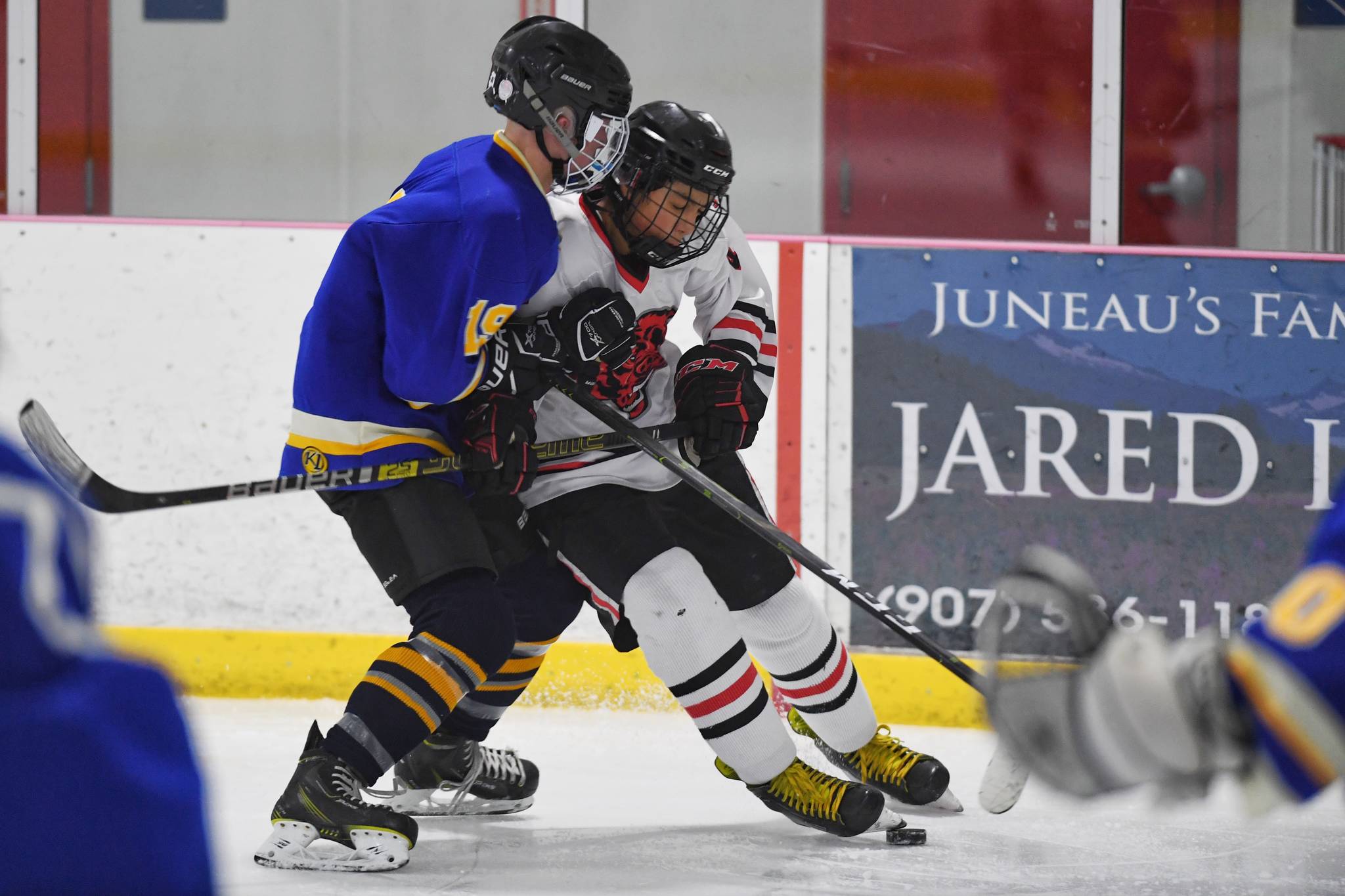 Juneau-Douglas’ Andre Peirovi, right, gets tied up against Monroe’s Dom Coiley in the second period of the first hockey game of the season on Friday, Nov. 15, 2019. (Michael Penn | Juneau Empire File)