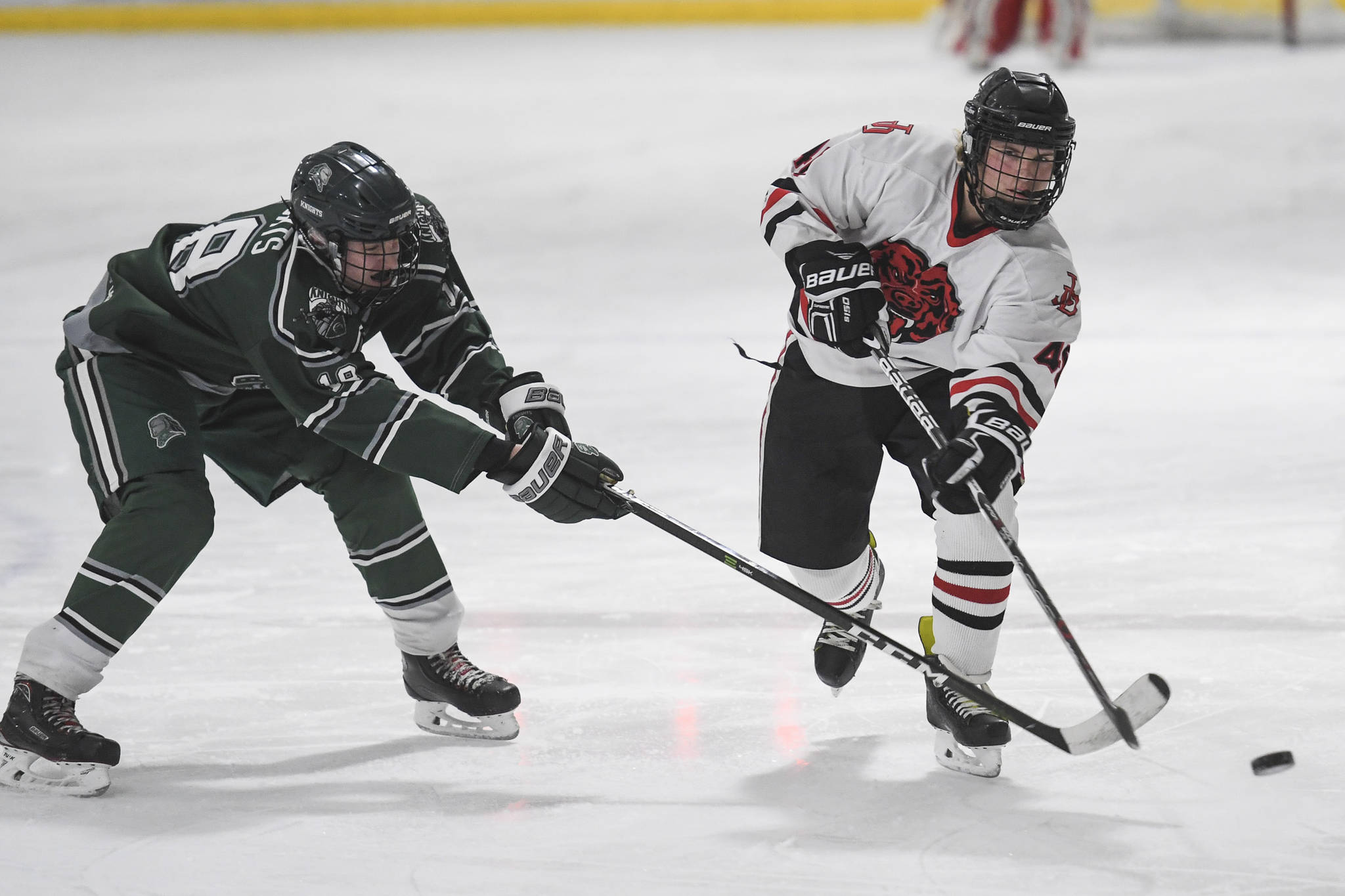 Juneau-Douglas’ Ethan Welch, right, passes the puck against Colony’s Tyler Keefe at Treadwell Arena on Friday, Nov. 22, 2019. (Michael Penn | Juneau Empire)