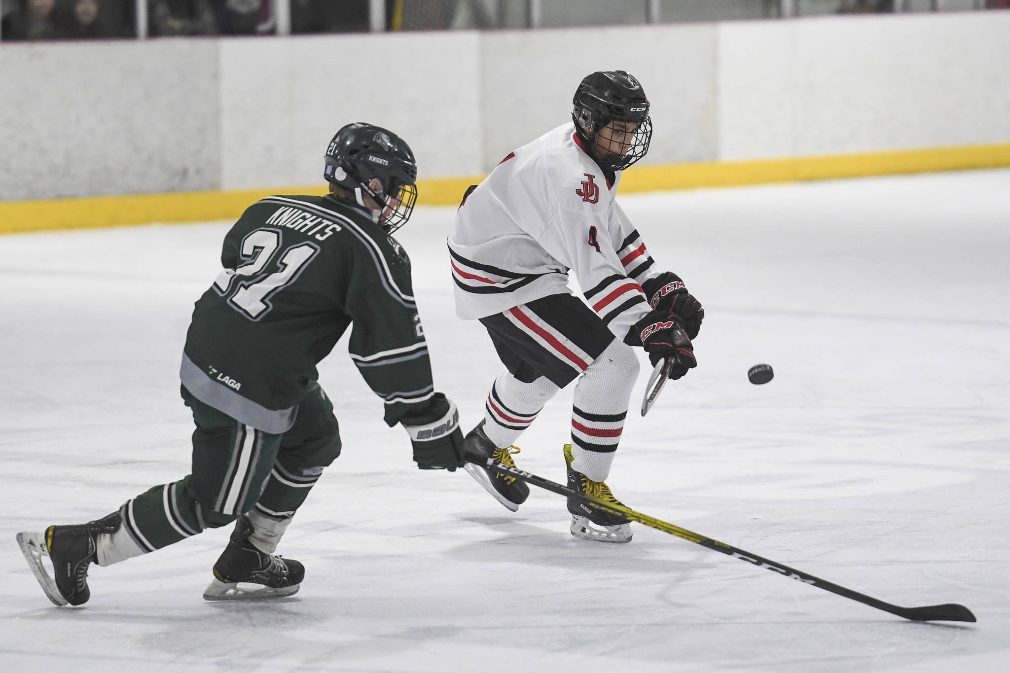 Juneau-Douglas’ Andre Peirovi, right, flicks the puck away from Colony’s Jacob Ross at Treadwell Arena on Friday, Nov. 22, 2019. (Michael Penn | Juneau Empire)