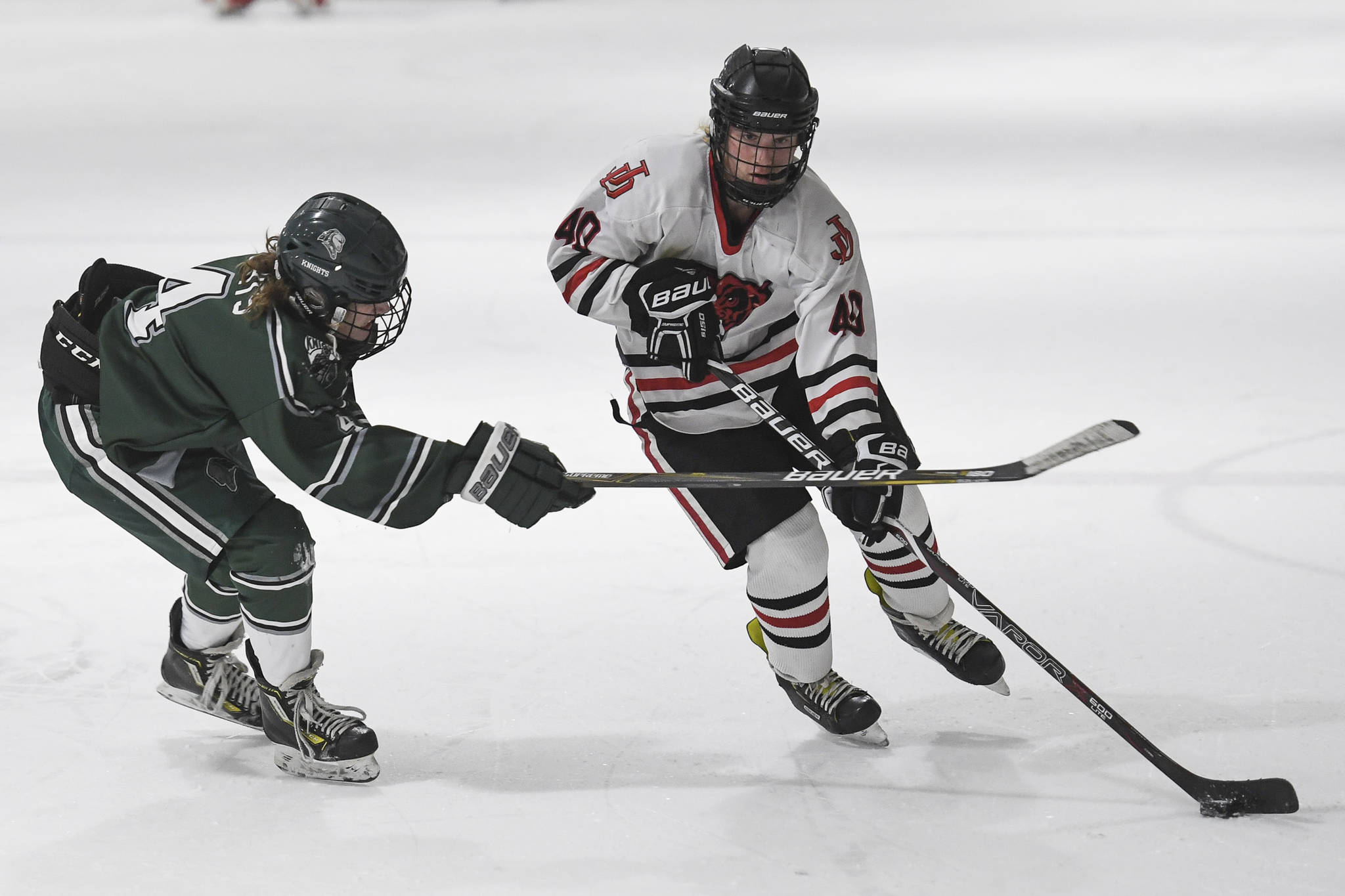 Juneau-Douglas’ Ethan Welch, right, passes the puck against Colony’s Benjamin Loggins at Treadwell Arena on Friday, Nov. 22, 2019. (Michael Penn | Juneau Empire)