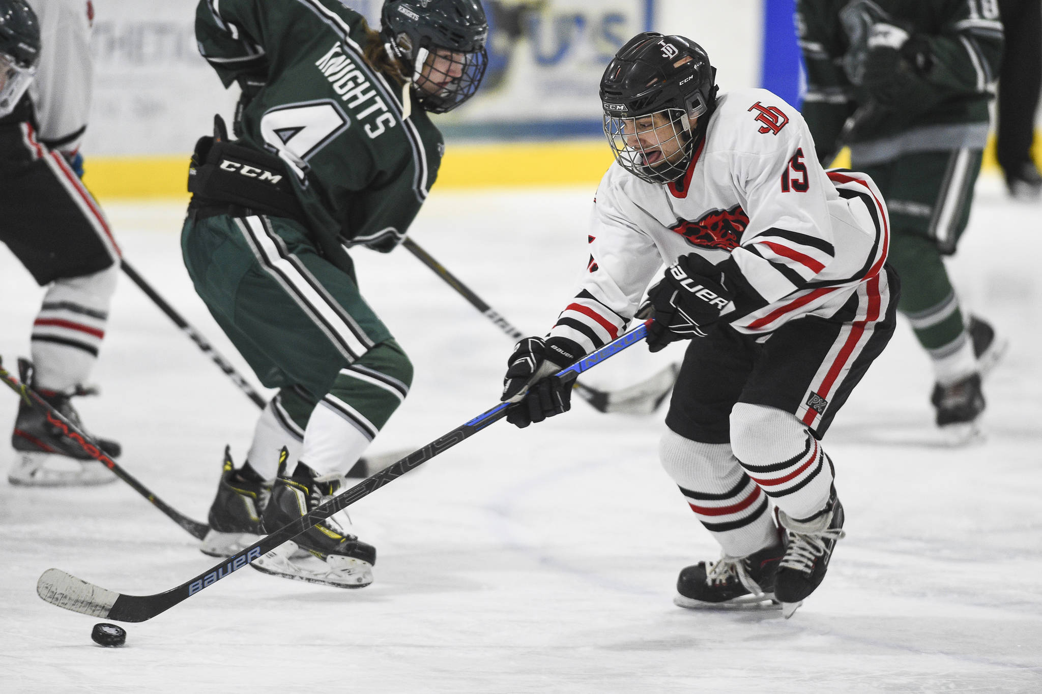 Juneau-Douglas’ Josh Frisby, right, moves the puck by Colony’s Benjamin Loggins at Treadwell Arena on Friday, Nov. 22, 2019. (Michael Penn | Juneau Empire)