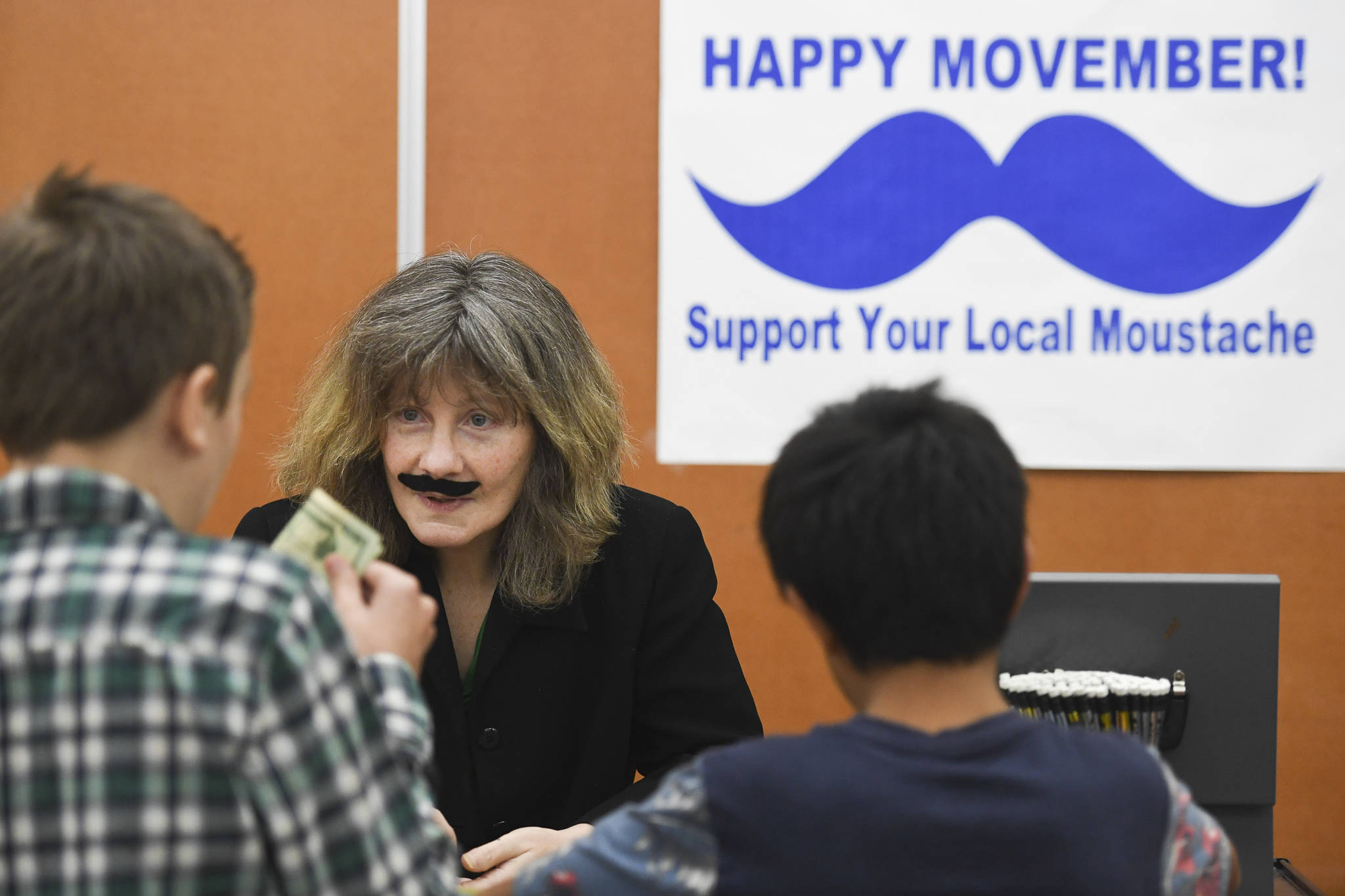 Barb Conant sells mustaches to students for Movember during their lunch hour at Floyd Dryden Middle School on Friday, Nov. 22, 2019. (Michael Penn | Juneau Empire)