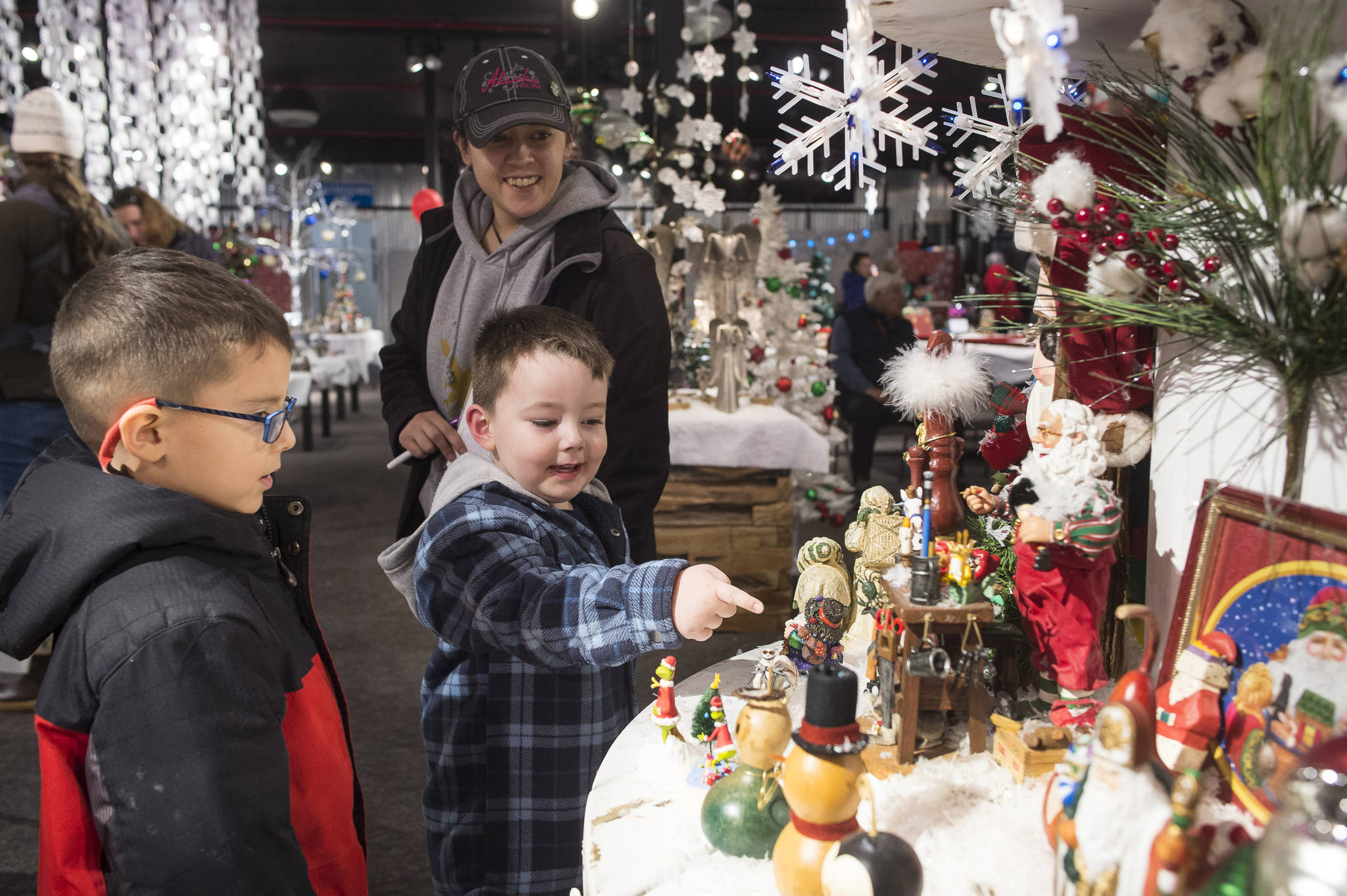 Delilah Bernaldo watches Kale Smith, 6, center, and Alec Muldoon, 4, as they look at the display at Holiday Village in the Alaska Shirt Company in December 2017. The village is a fundraiser for the Southeast Alaska Food Bank, Meals on Wheels, AWARE and The Glory Hall. (Michael Penn | Juneau Empire File)
