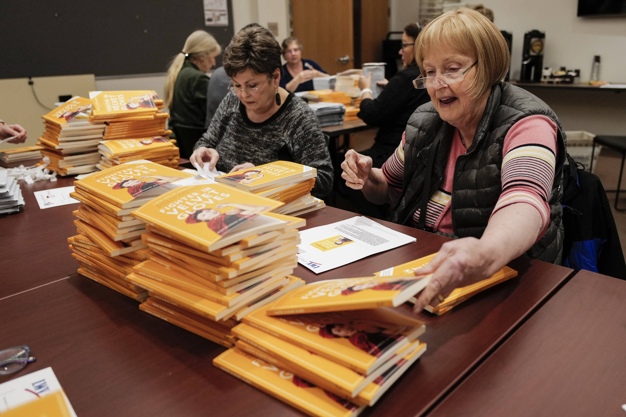 League of Women Voters of Juneau volunteers Karen Crane, left, Cheryl Jebe and others prepare Annie Boochever’s book about civil rights leader Elizabeth Peratrovich, “Fighter in Velvet Gloves,” for mailing at the Andrew P. Kashevaroff Building on Monday, Dec. 2, 2019. Over 450 copies of the book were packaged to be shipped to libraries and school across Alaska. (Michael Penn | Juneau Empire)