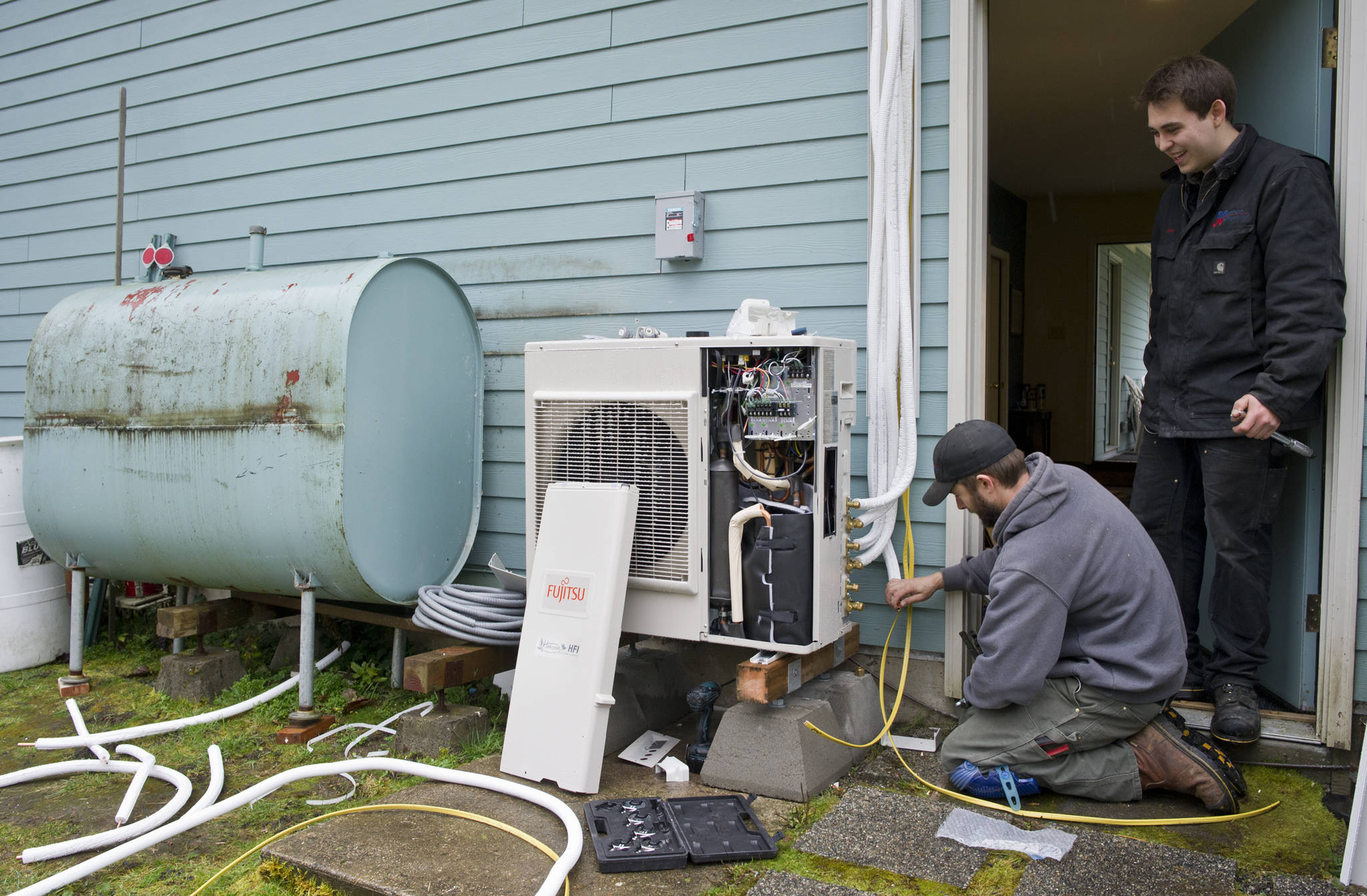 Jake Eames, right, and David Nash install an air-to-air heat pump system to a Mendenhall Valley home Thursday that formerly was using oil for heating in 2015. (Michael Penn | Juneau Empire)