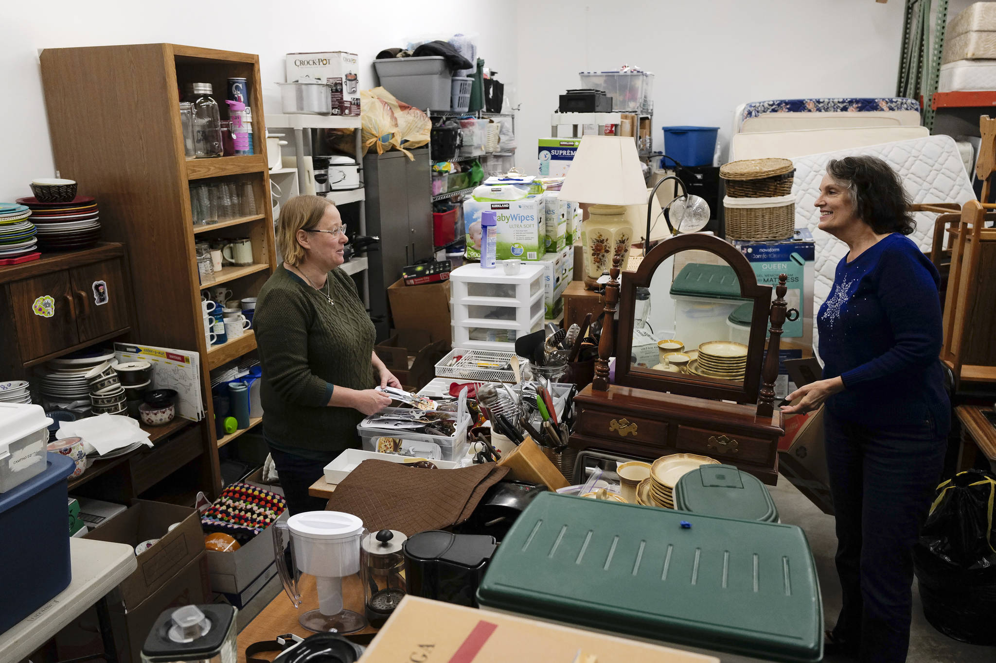 Resource Coordinator Anne Edwards, left, and Cleaning House Coordinator Karen Parker go through donated houseware items at Love, Inc. on Friday, Dec. 6, 2019. Love, Inc., works as a clearinghouse to receive requests for assistance and eliminate duplicated services between churches and community agencies. (Michael Penn | Juneau Empire)