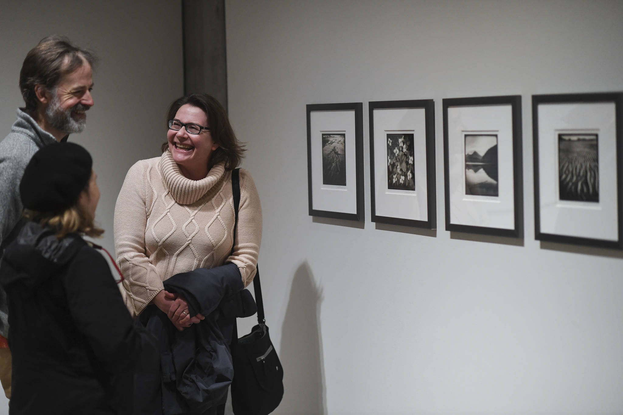 Iris Korhonen-Penn, right, talks with friends Mike Hekkers and Di Johnson about her work at the Alaska Positive juried photography exhibit at the Alaska State Museum during Gallery Walk on Friday, Dec. 6, 2019. Korhonen-Penn of Juneau received an Award of Recognition for her set of four pictures. (Michael Penn | Juneau Empire)