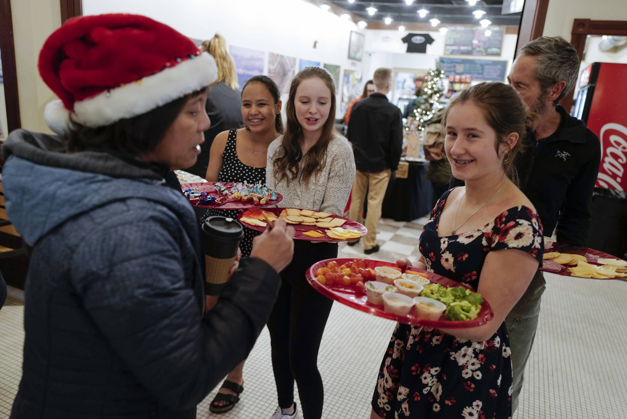 Adelie McMillian, right, Lydia Powers, center, and Dominique Morley, all members of figure skating team, serve trays of treats to visitors to the Senate Building during Gallery Walk on Friday, Dec. 6, 2019. (Michael Penn | Juneau Empire)