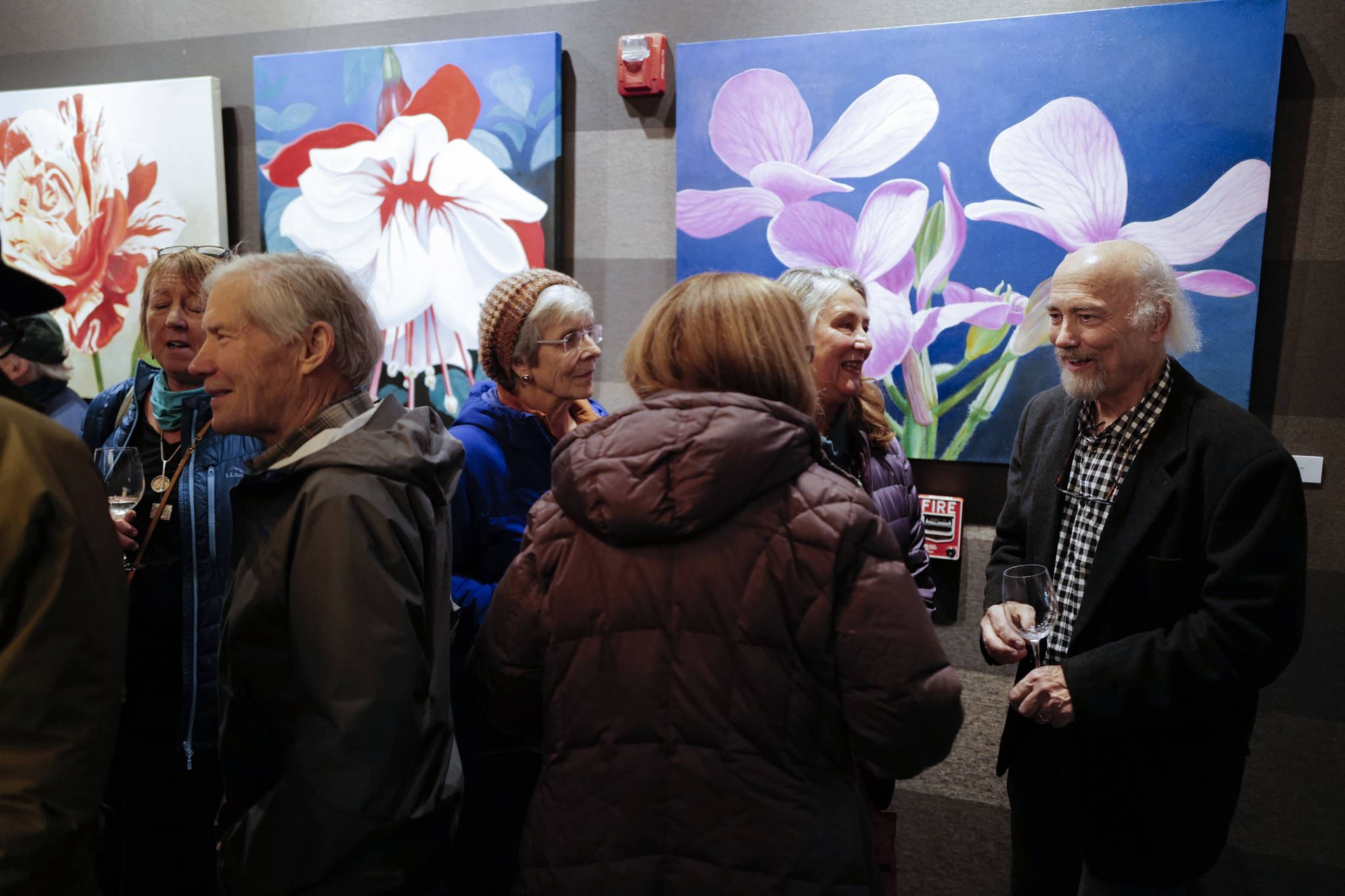 Dan DeRoux, right, talks with visitors to his “Power Flowers” exhibit at Salt during Gallery Walk on Friday, Dec. 6, 2019. (Michael Penn | Juneau Empire)