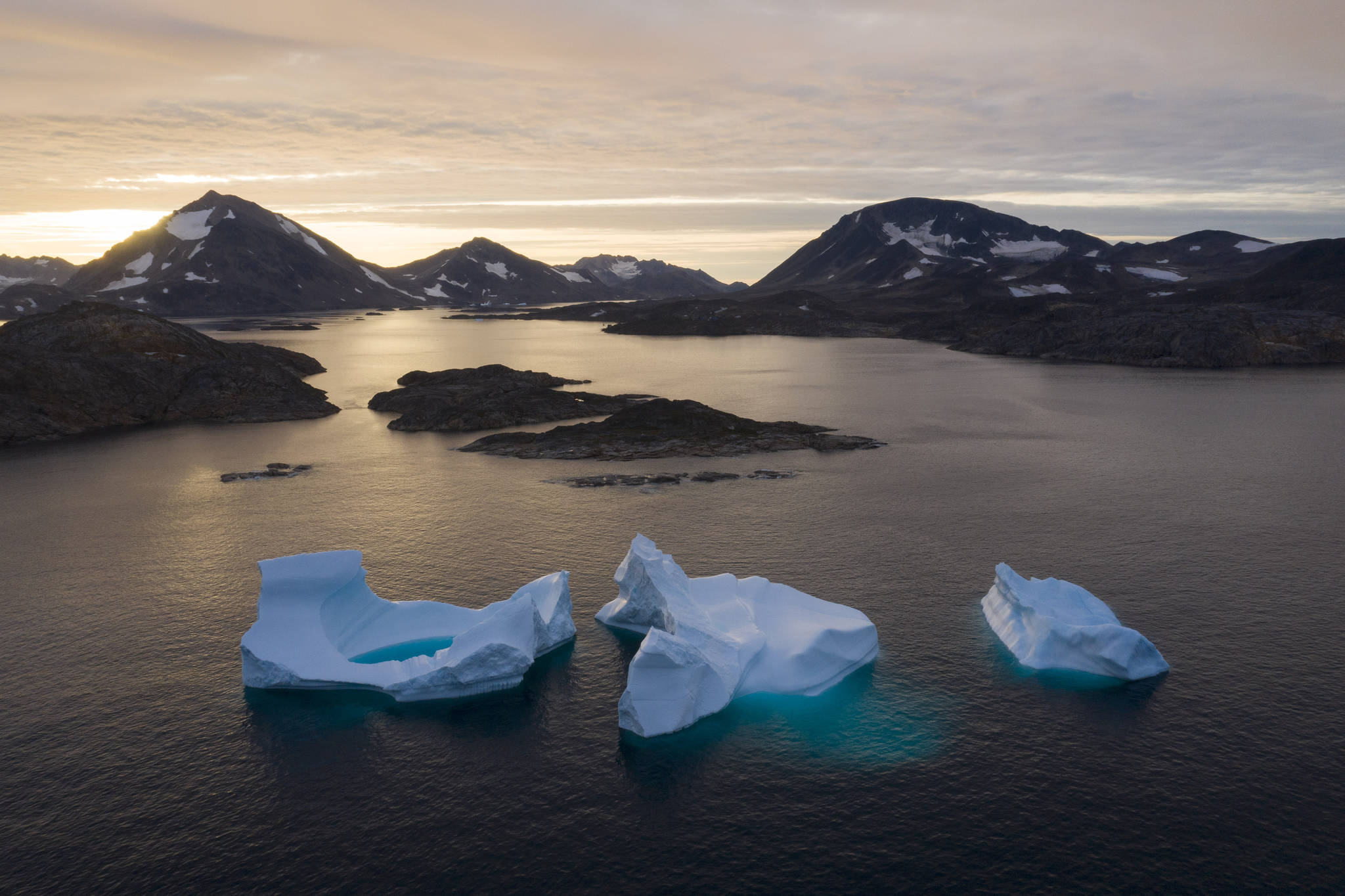 In this Aug. 16 photo, large icebergs float away as the sun rises near Kulusuk, Greenland. Rising temperatures and diminished snow and ice cover in the Arctic are imperiling ecosystems, fisheries and local cultures, according to a report issued Tuesday, Dec. 10 by the National Oceanic and Atmospheric Administration. (AP Photo/Felipe Dana, File)