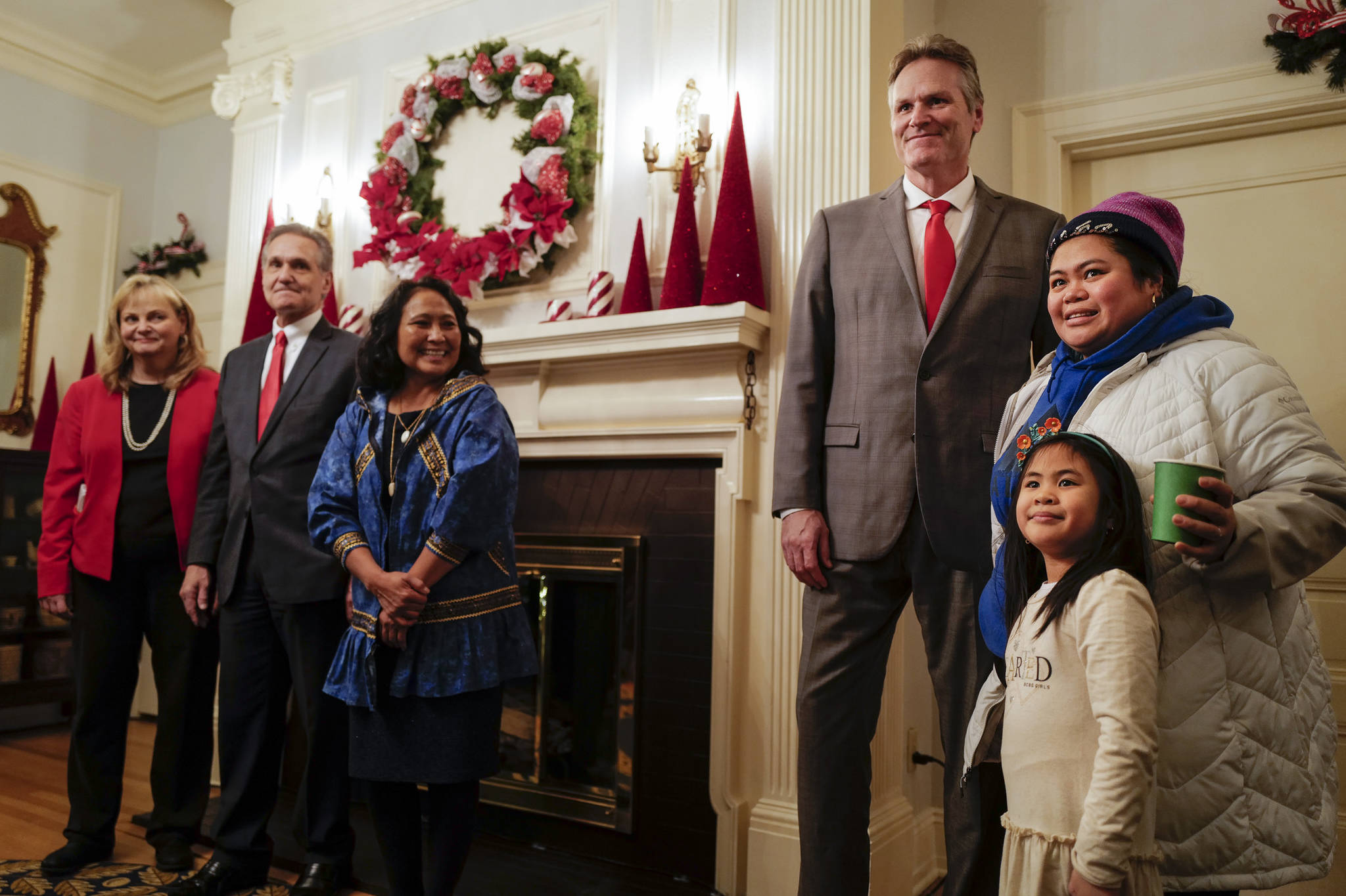 Gov. Mike Dunleavy, R-Alaska, poses for a picture with Marnellie Remeualt and her daughter, Mara, 5, as Gov. Dunleavy’s wife, Rose, Lt. Gov. Kevin Meyer and his wife, Marti, look on at the Governor’s Open House on Tuesday, Dec. 10, 2019. (Michael Penn | Juneau Empire)