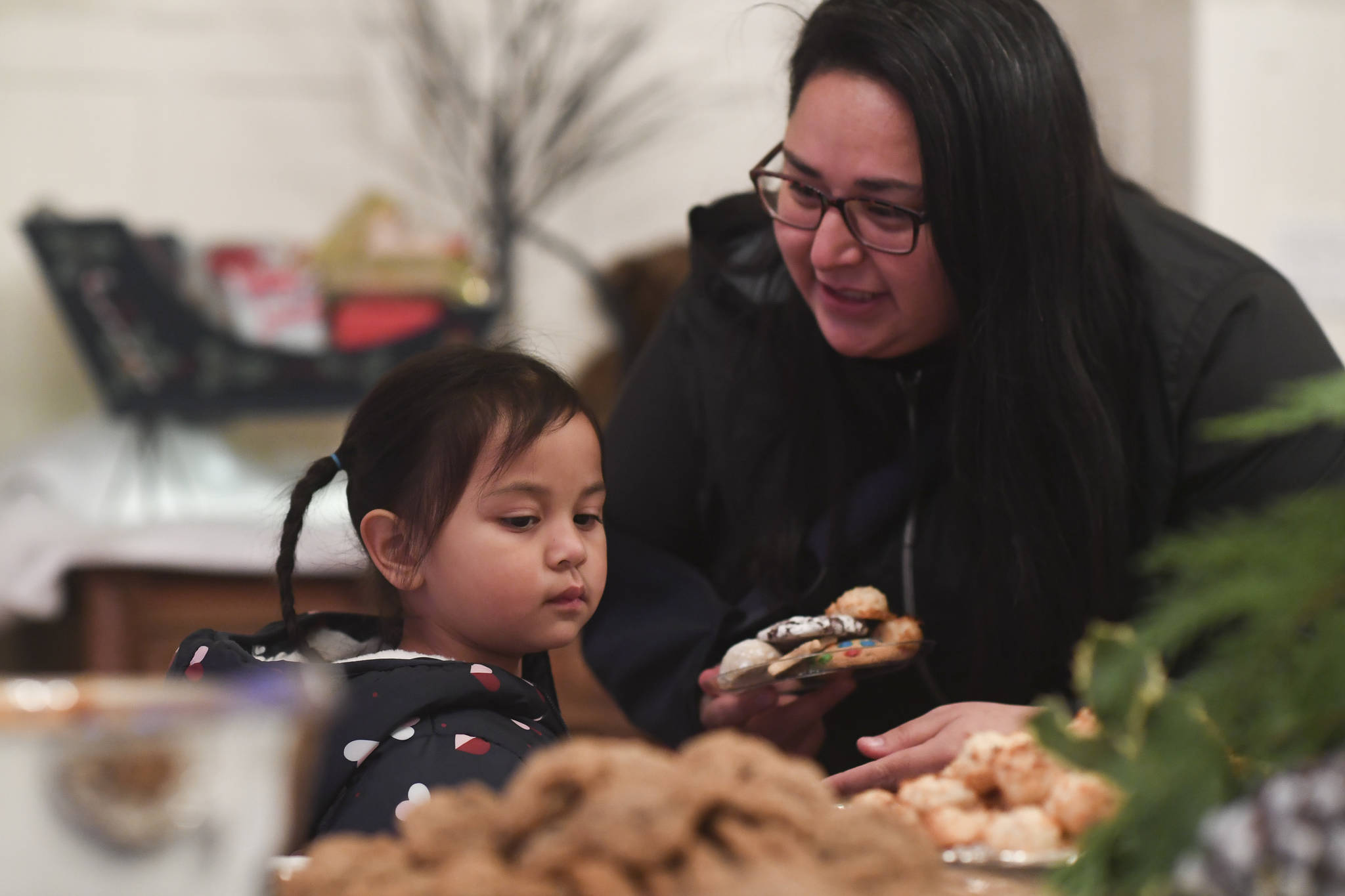 Shakira Vallejo helps her daughter, Gabriela, 4, choose their cookies at the Governor’s Open House on Tuesday, Dec. 10, 2019. (Michael Penn | Juneau Empire)