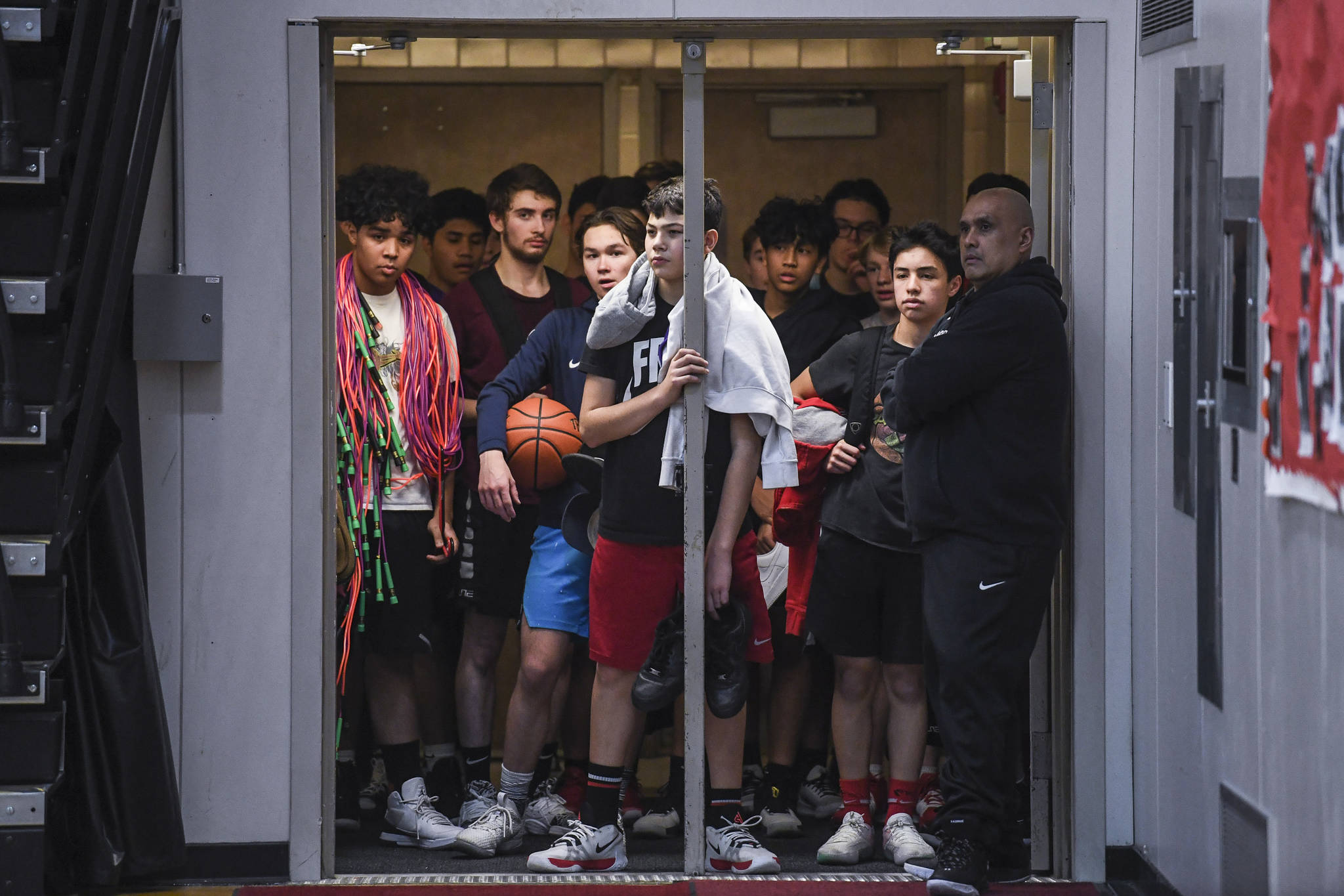 The boys junior varsity basketball team waits for their time on the court as the girls varsity basketball team finishes their practice at Juneau-Douglas High School: Yadaa.at Kalé on Monday, Dec. 9, 2019. (Michael Penn | Juneau Empire)