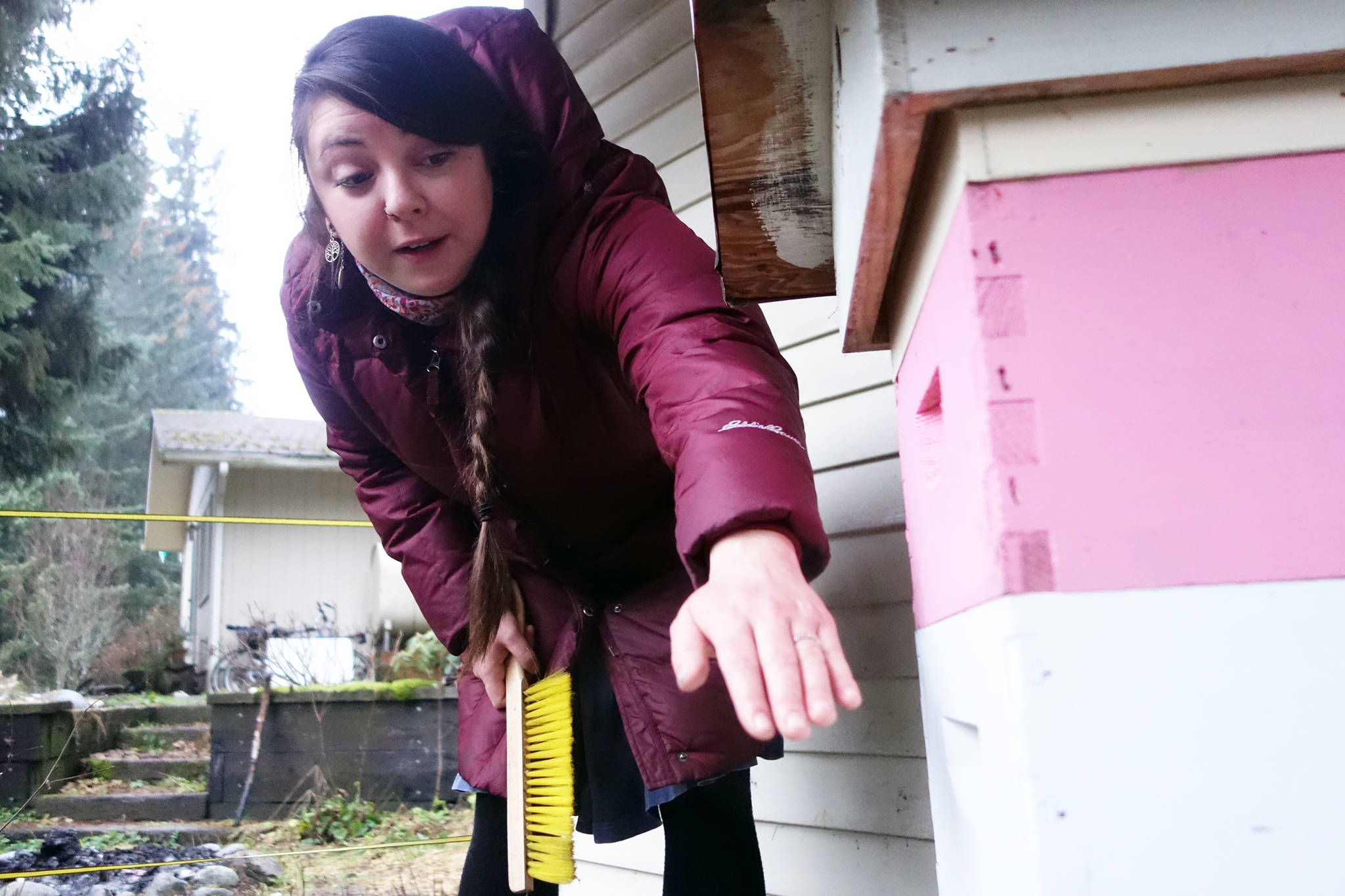 Raylynn Lawless, who keeps bees with her husband, Cody Barril, gestures toward the hive in her Mendenhall Valley backyard. (Ben Hohenstatt | Juneau Empire)