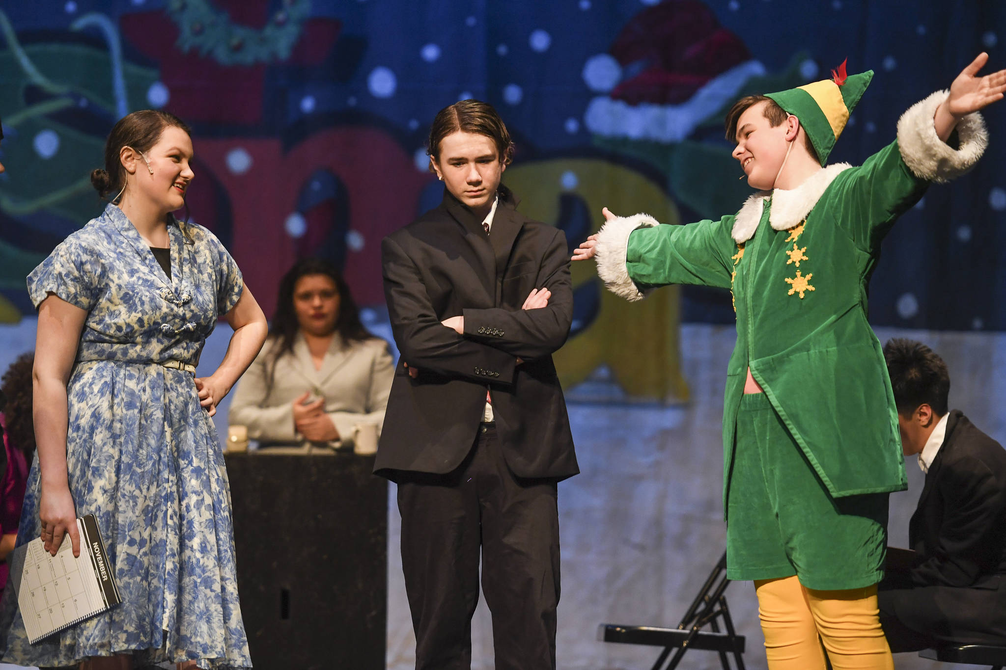 Emily Hobbs, played by Amanda McDowell, left, and her husband, Walter Hobbs, played by Jager Hunt, center, are introduced to Buddy the Elf, played by Toby Russell, during rehearsal of “Elf, the Musicial” at Juneau-Douglas High School: Yadaa.at Kalé on Friday, Dec. 13, 2019. (Michael Penn | Juneau Empire)