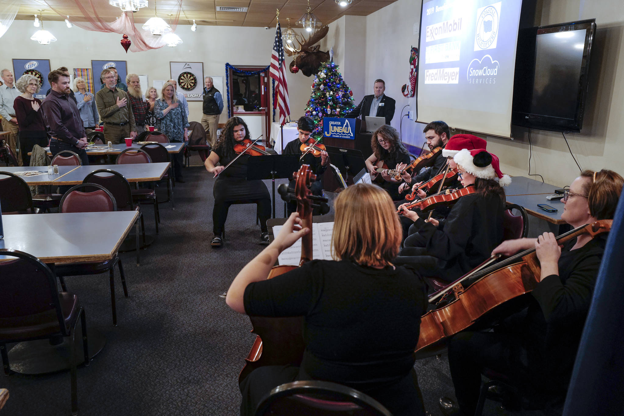 Meghan Johnson, executive director of Juneau Alaska Music Matters (JAMM), right, plays the National Anthem with high school freshmen who started their music careers in the JAMM program on Thursday, Dec. 19, 2019. The students were part of the presentation Johnson, and Program Director Lorrie Heagy to the Juneau Chamber of Commerce during its luncheon at the Moose Lodge. (Michael Penn | Juneau Empire)