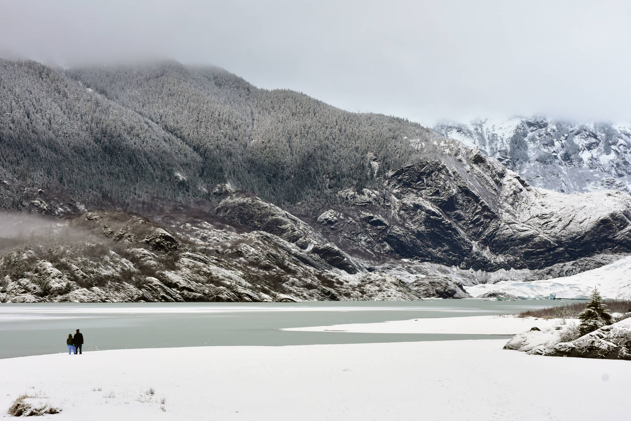 A couple stands on a frozen portion of Mendenhall Lake on Sunday, Dec. 22, 2019. (Peter Segall | Juneau Empire)