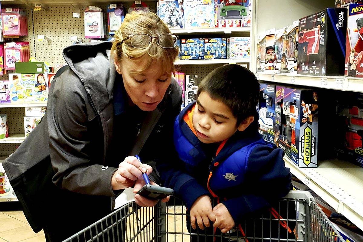 Erann Kalwara, public safety manager with the Juneau Police Department, helps a child pick out Christmas presents for their families during the annual Shop with a Cop event, sponsored by the Alaska Peace Officer Association, at Fred Meyer on Dec. 21, 2019. (Courtesy photo | Juneau Police Department)