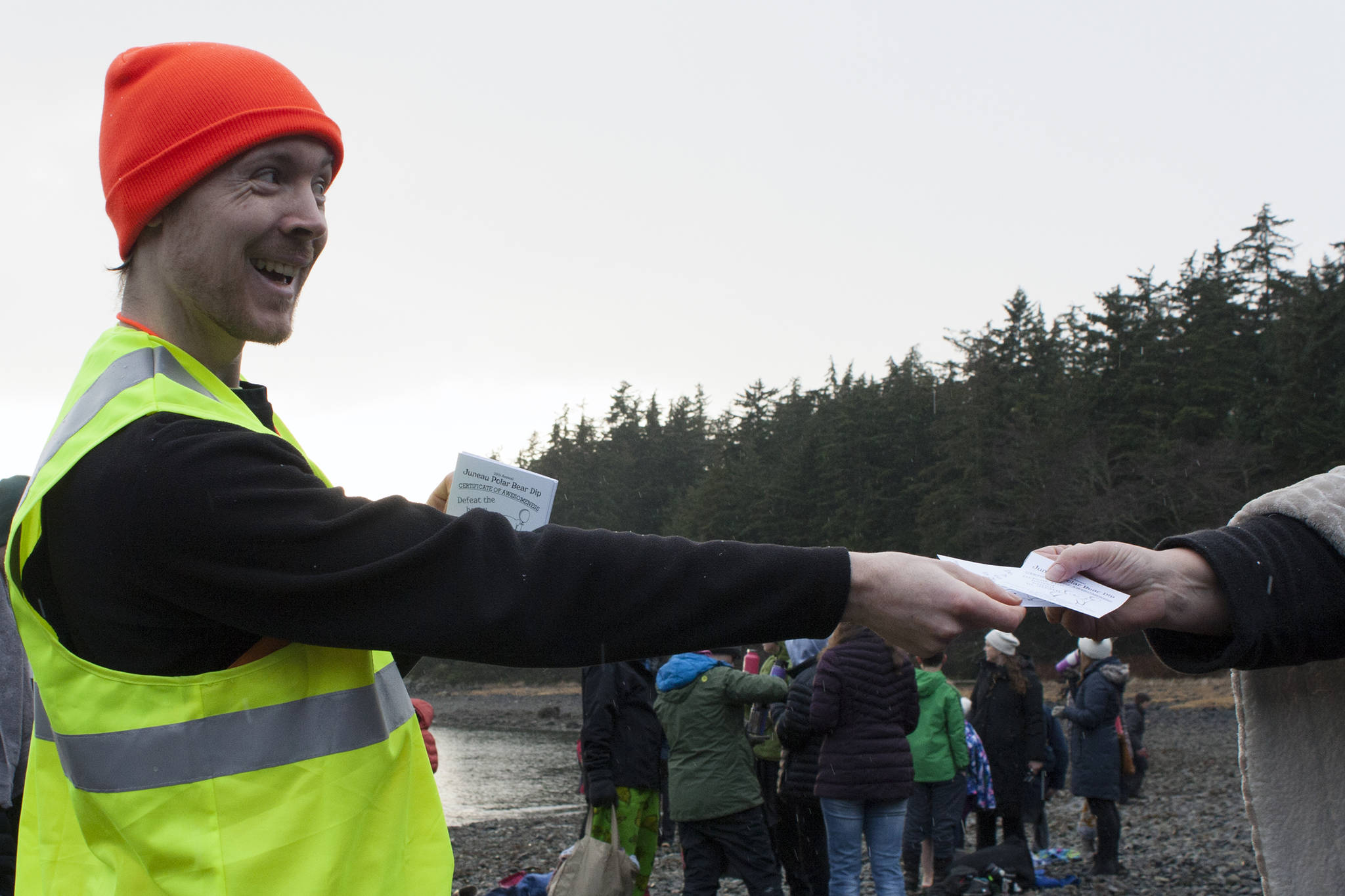 Carl Brodersen hands out a certificate of awesomeness to a participant in the 2020 Polar Dip. (Ben Hohenstatt | Juneau Empire)