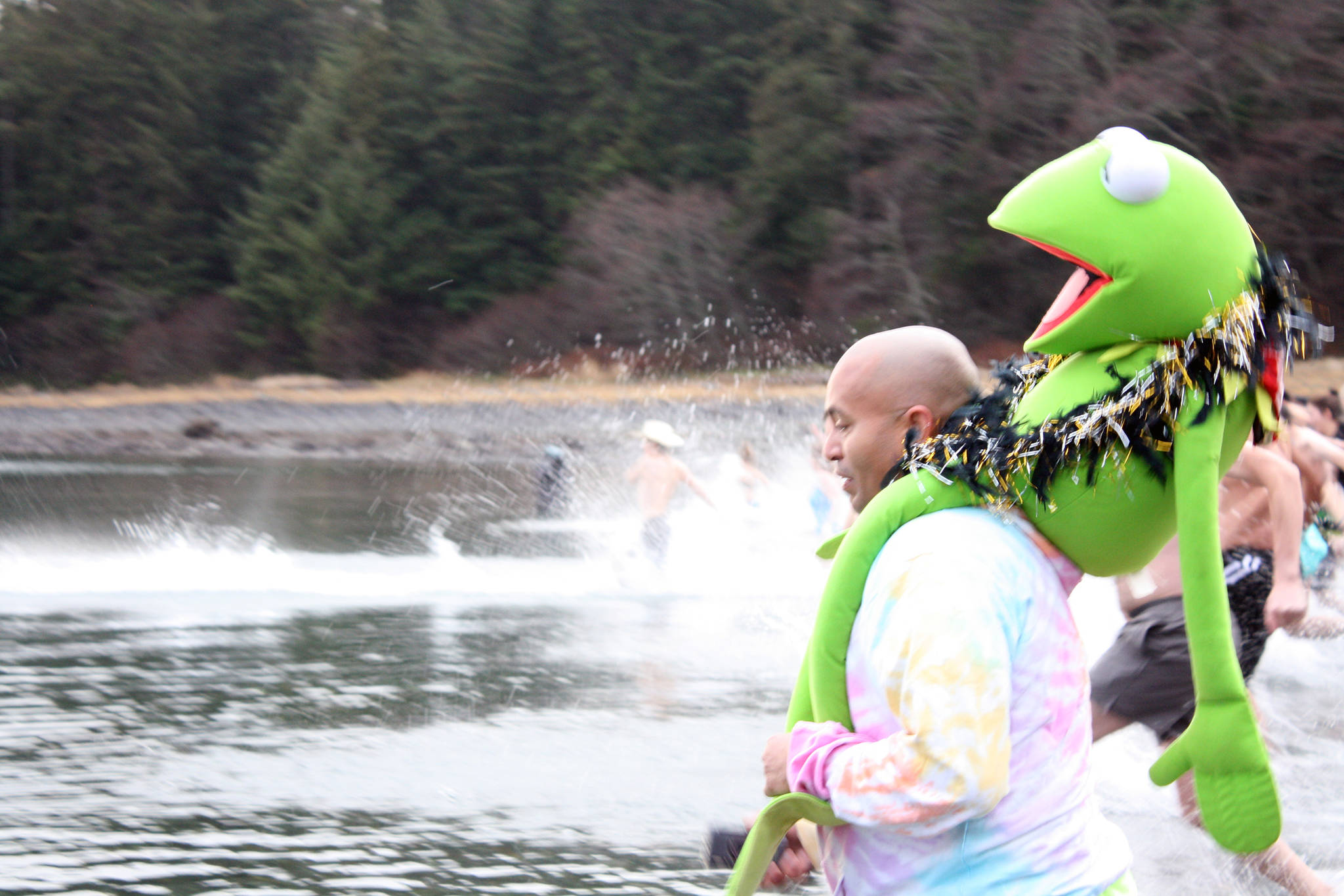 Courtney Pegus with a stuffed Kermit on his shoulders and other Polar Dip participants start off 2020 with a charge into the water at Auke Bay Recreation Area. (Ben Hohenstatt | Juneau Empire)