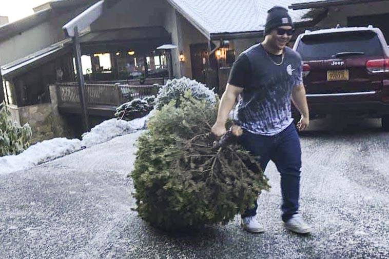 Dylan Vernon, a student at Juneau-Douglas High School: Yadaa.at Kalé and member of the cheer team, collects a dead Christmas tree as part of a fundraiser for the team during 2019. (Natalie Zimmerman | Courtesy photo)