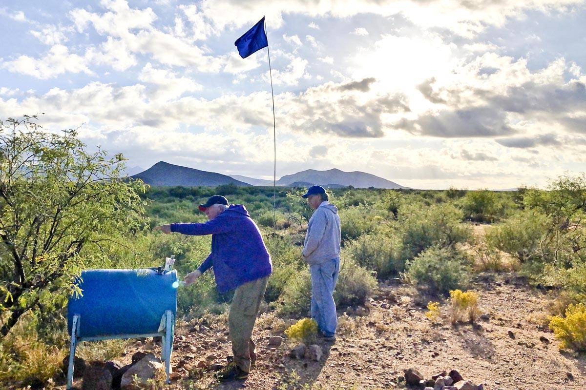 Volunteers from Humane Borders, a charitable organization, fill a water drum in the Arizona desert for immigrants traveling the waste. (Ken Huse | Courtesy Photo)