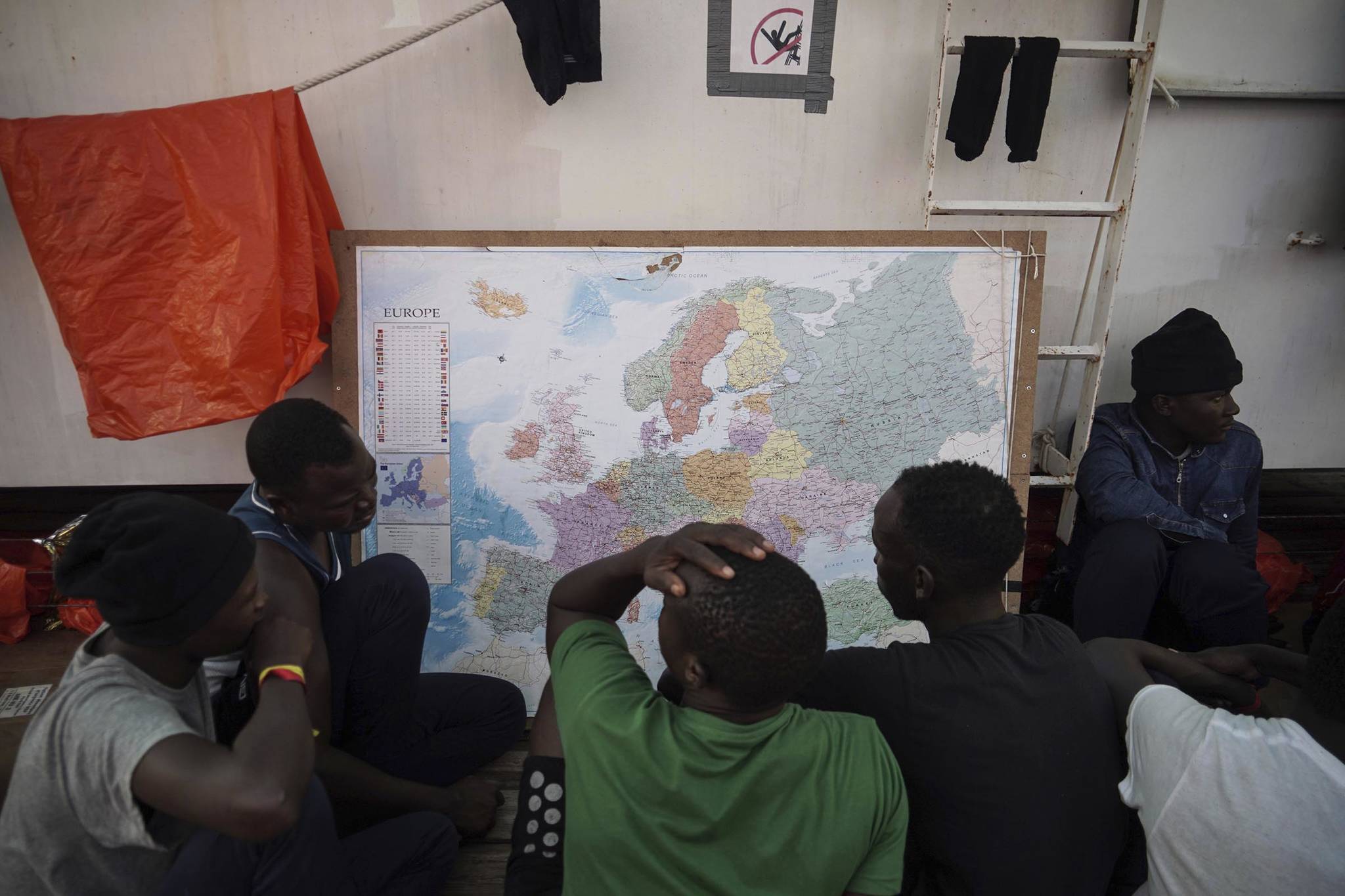 In this Sept. 23 photo, rescued migrants look at a map of Europe aboard the Ocean Viking humanitarian ship as it sails in the Mediterranean Sea. (AP Photo | Renata Brito)