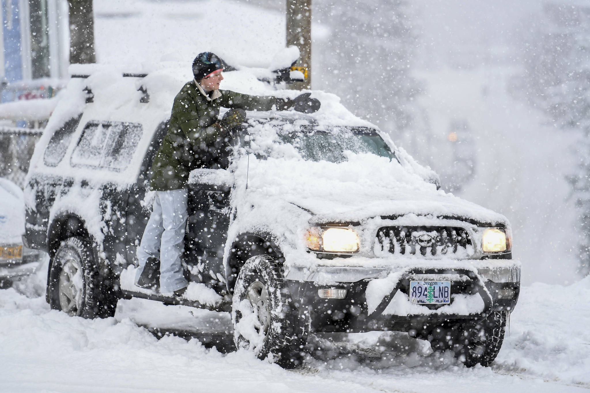 Malia Sutphin cleans snow off her truck on Distin Avenue on Tuesday, Jan. 7, 2020. (Michael Penn | Juneau Empire)