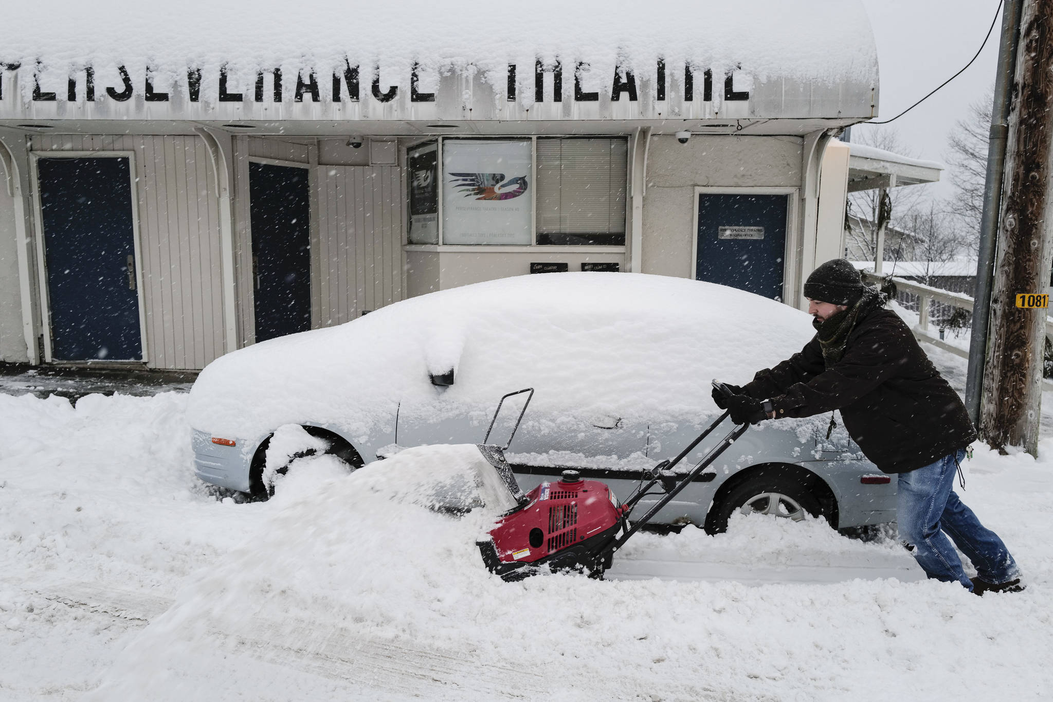 Evan Price, the technical director for Perseverance Theatre, removes snow from the front of the theater on Tuesday, Jan. 7, 2020. (Michael Penn | Juneau Empire)