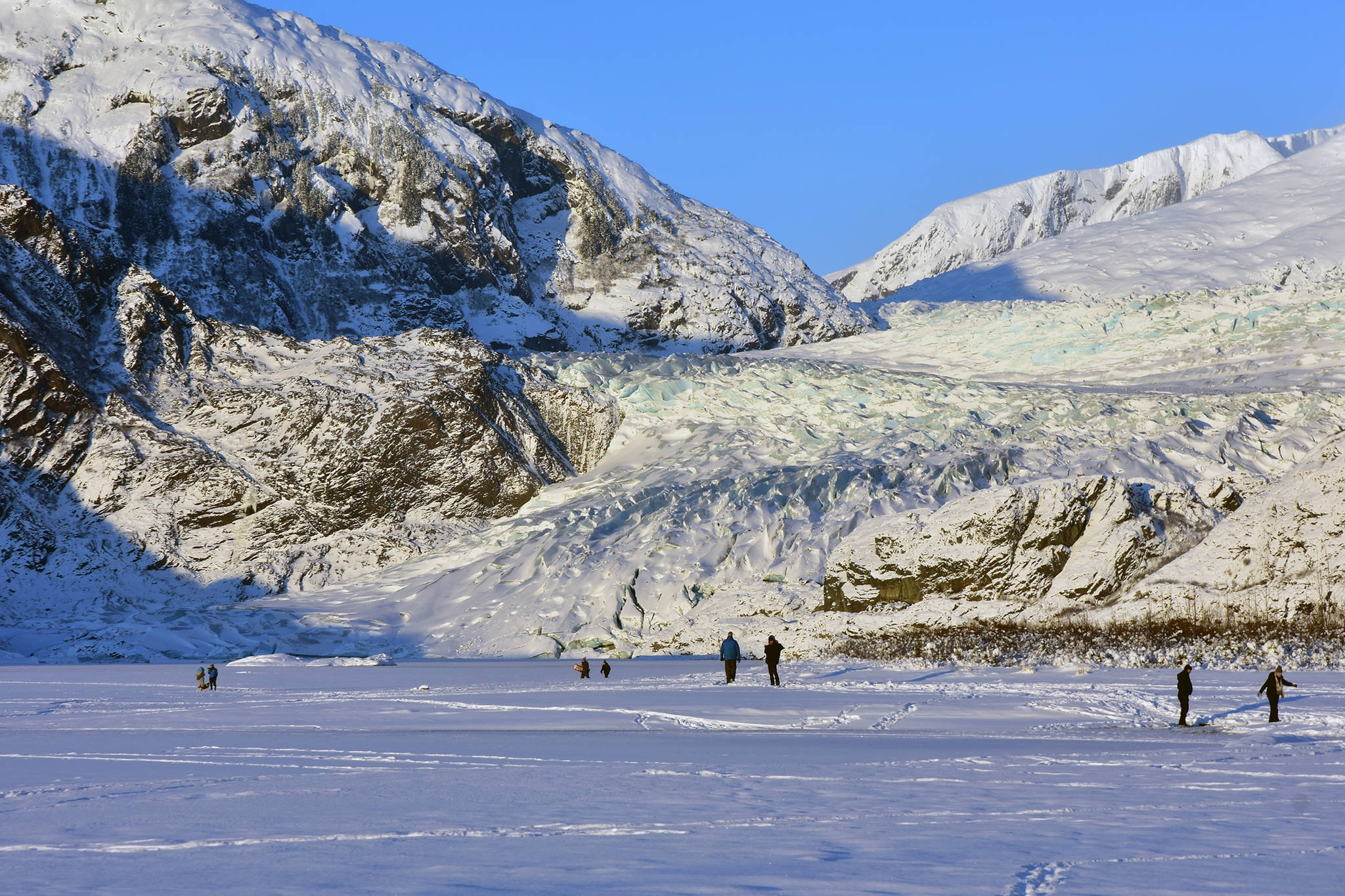 People walk on the ice at Mendenhall Lake, Saturday, Jan. 11. Despite a recent cold spell, the ice is not yet thick enough to support people in some spots. The U.S. Forest Service and Capital City Fire/Rescue both advise staying off the ice. (Peter Segall | Juneau Empire)
