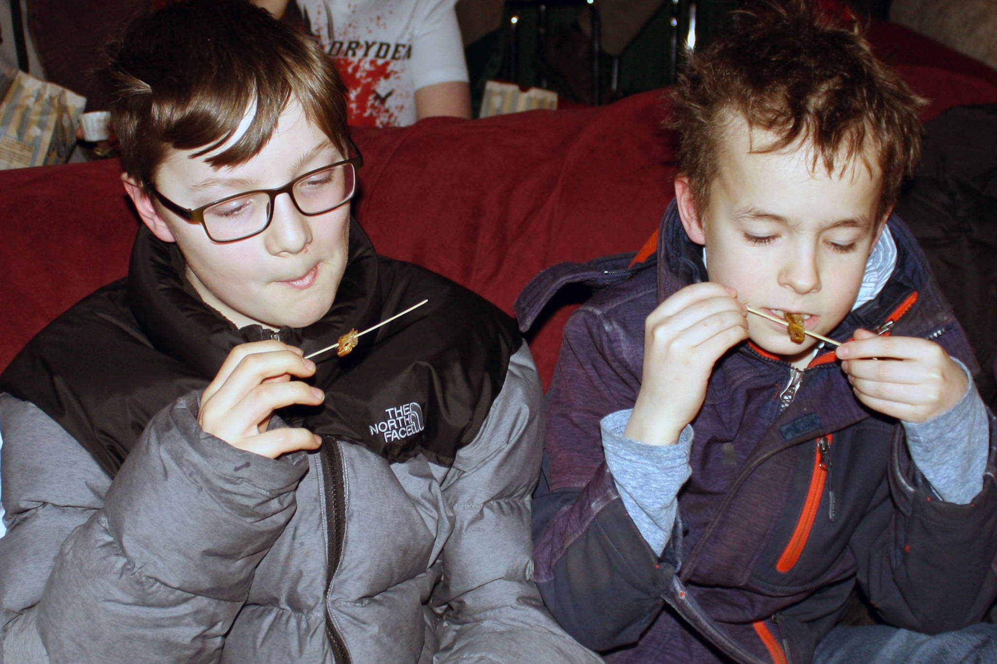 Arlo Davis, 11, and Axel Boily, 10, chow down on farm-raised locusts at the Gold Town Theater, Saturday, Jan. 18, 2020. (Ben Hohenstatt | Juneau Empire)